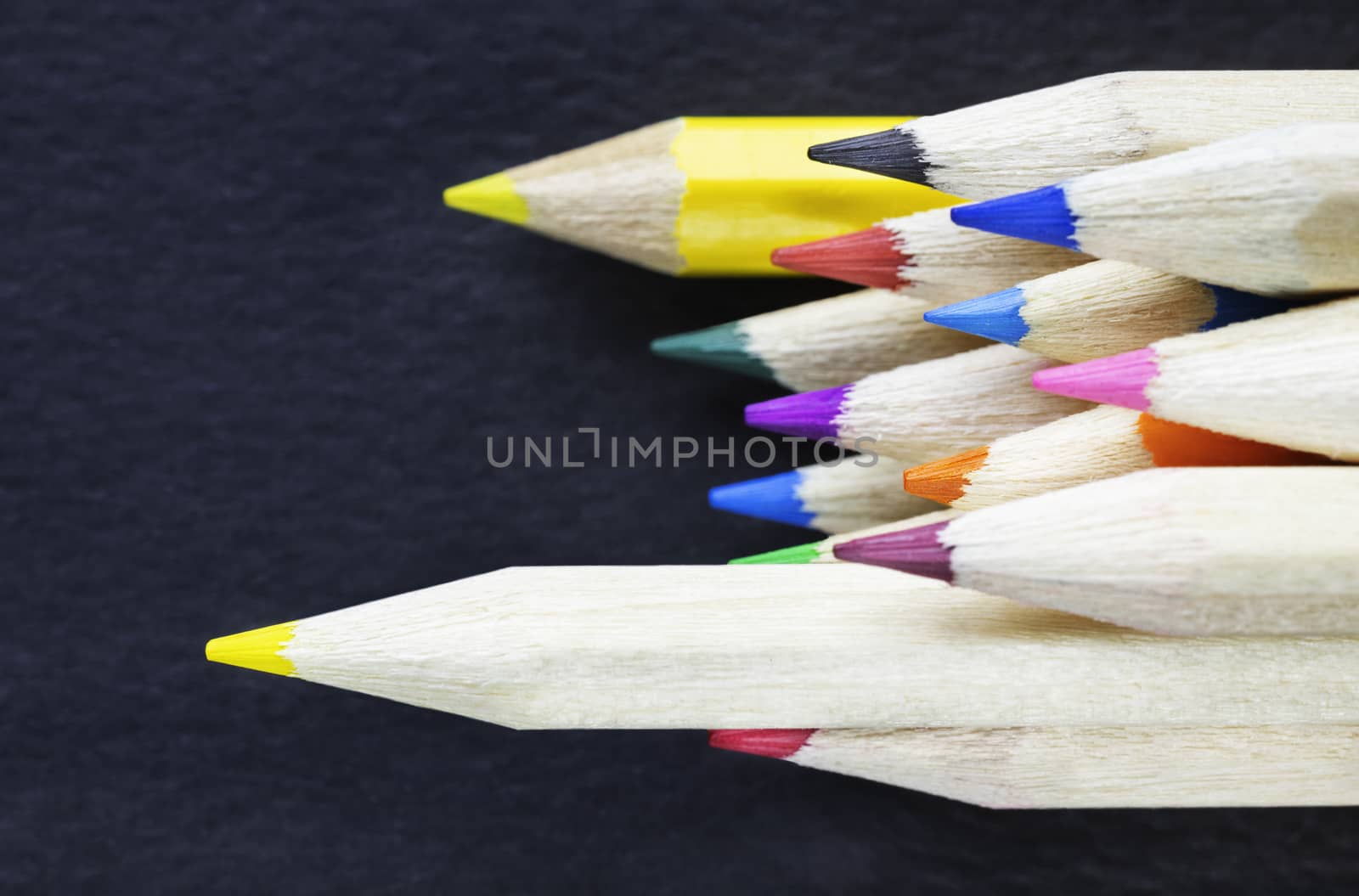 Multicolored pencils on a dark background , wooden pencils with colored points