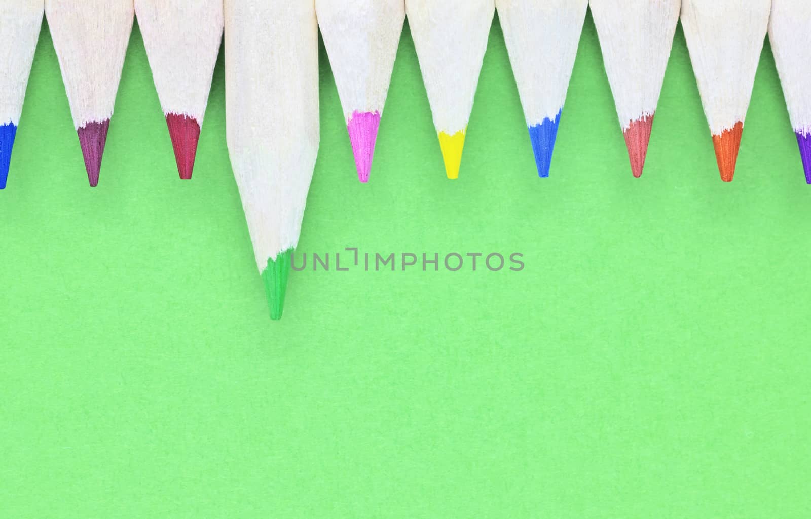 Multicolored pencils on green  background , wooden pencils with colored points in a row