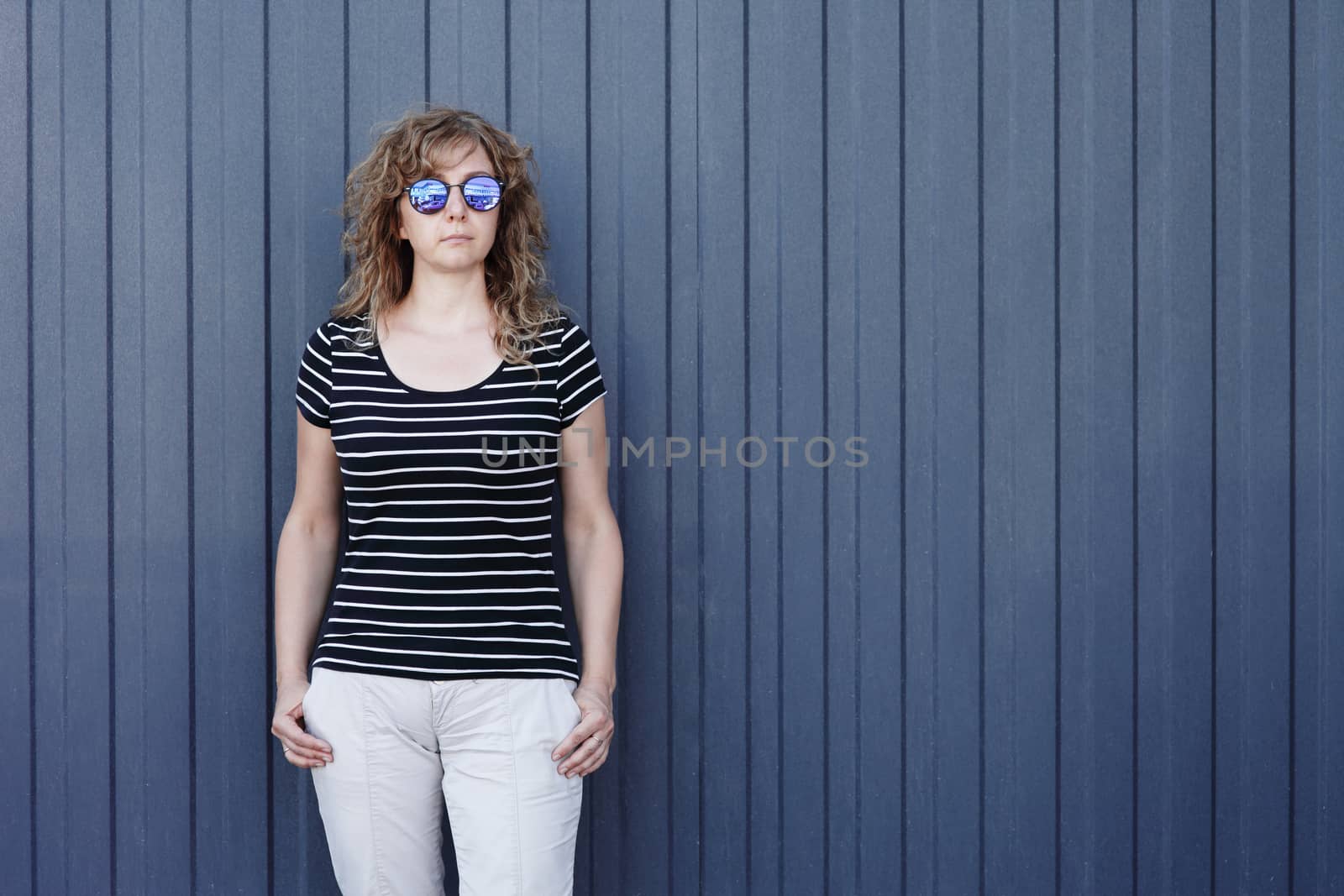 Woman portrait in sunglasses, free space for text. Blue striped wall in the background