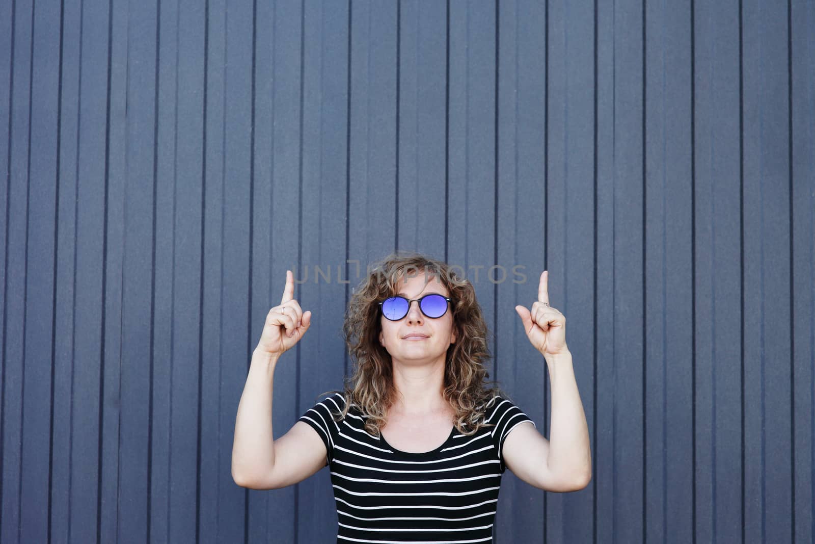 Woman portrait in sunglasses, free space for text. Blue striped wall in the background