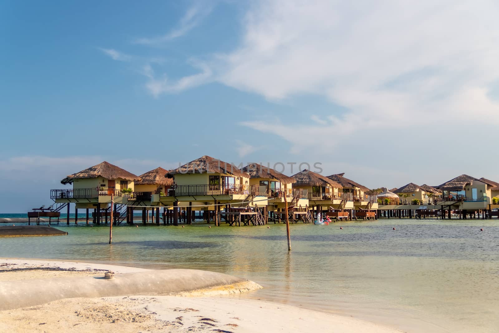 Water Villas (Bungalows) and wooden bridge at Tropical beach in the Caribbean sea by leo_de_la_garza