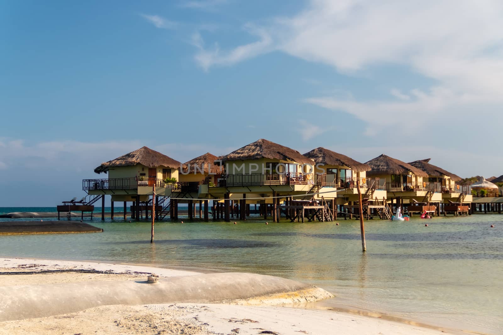 Water Villas (Bungalows) and wooden bridge at Tropical beach in the Caribbean sea at summer day