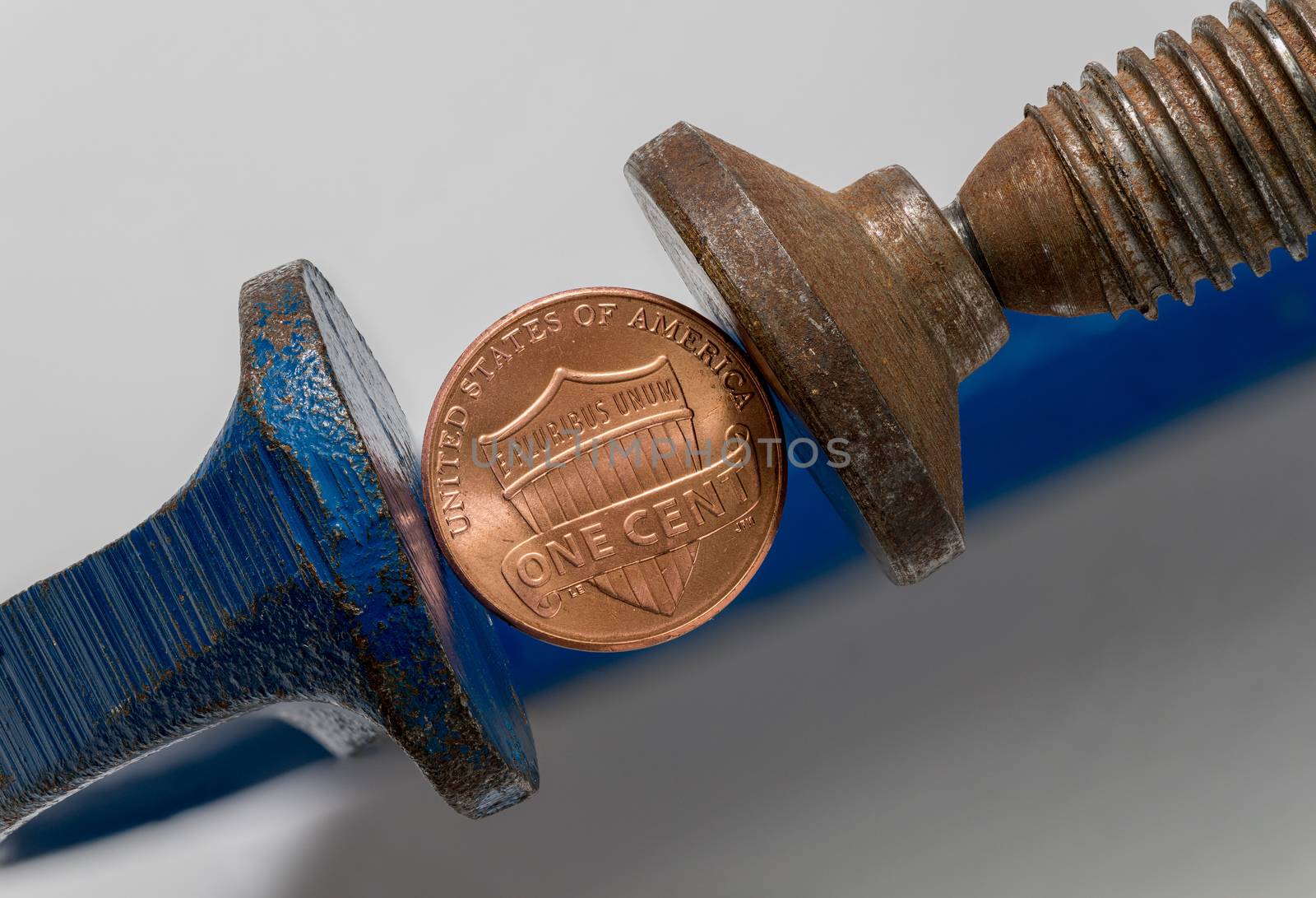 Concept for financial stress or recession. USA one cent coin being squeezed between the jaws of a large vise or vice in detailed macro shot