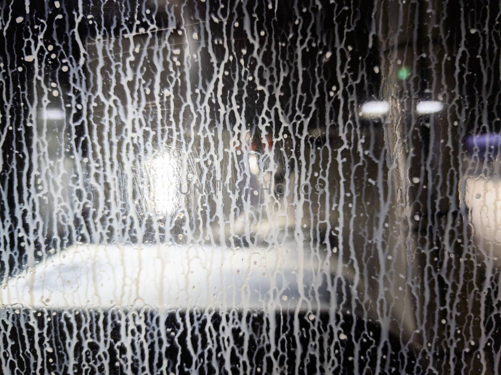 white water coolant emulsion streaming down on cnc machine polycarbonate window - closeup with selective focus