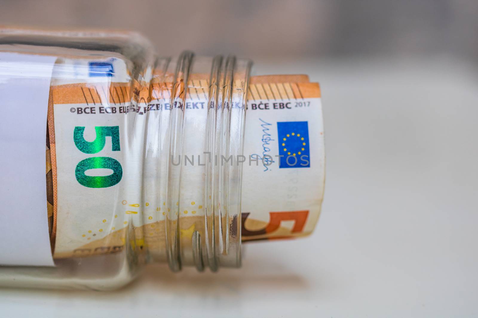 Composition with saving money banknotes (50 EURO) in a glass jar. Concept of investing and keeping money, close up isolated.