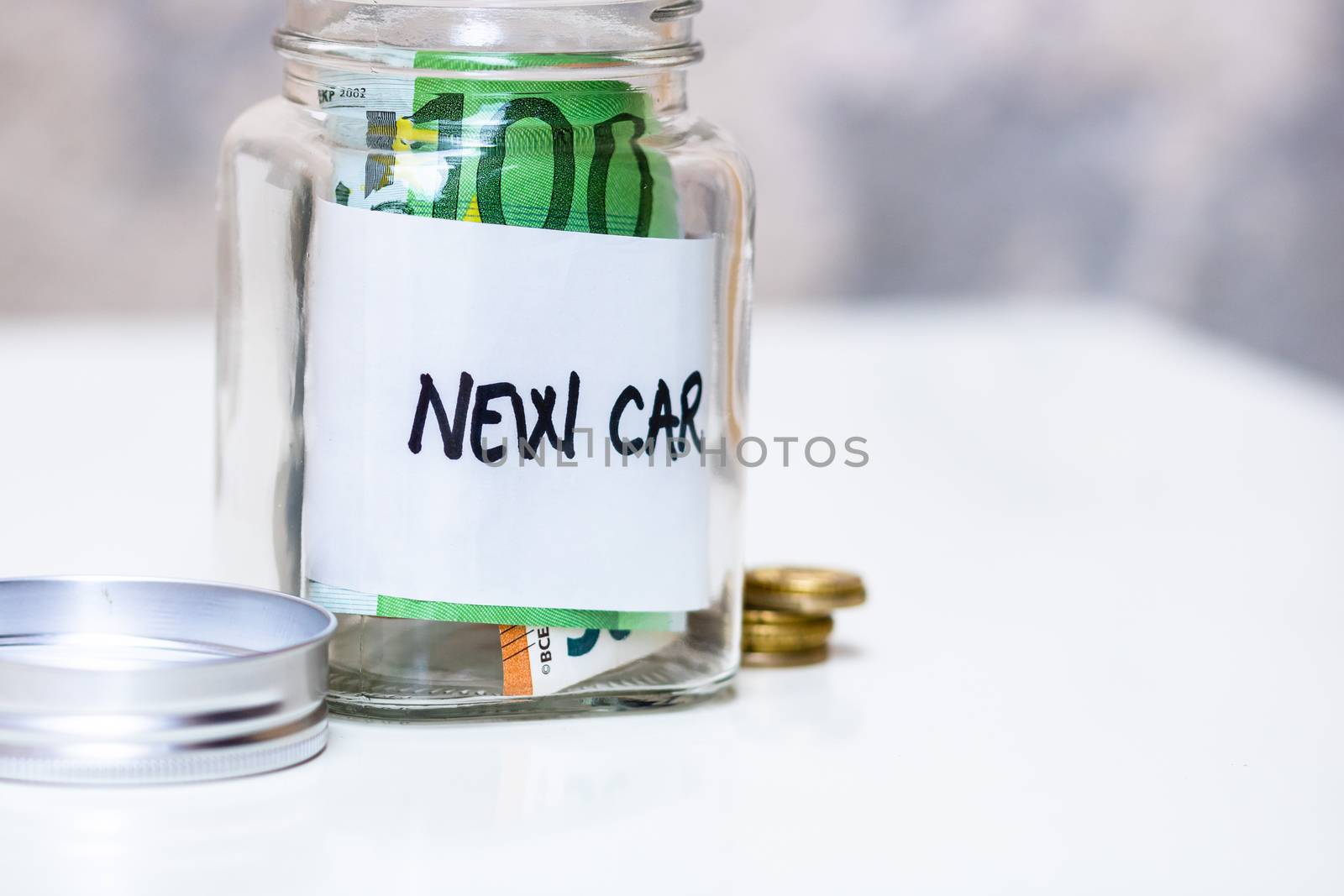 Composition with saving money banknotes in a glass jar with text new car .Concept of investing and keeping money, close up isolated.