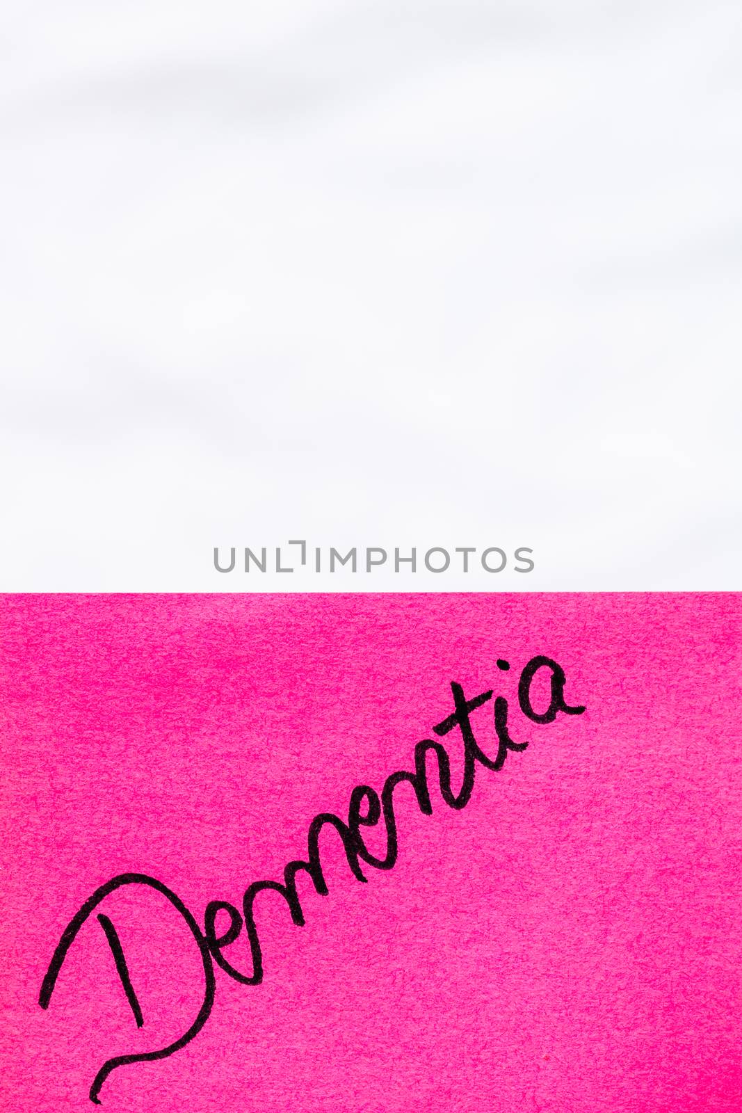 Dementia handwriting text close up isolated on pink paper with copy space. Writing text on memo post reminder