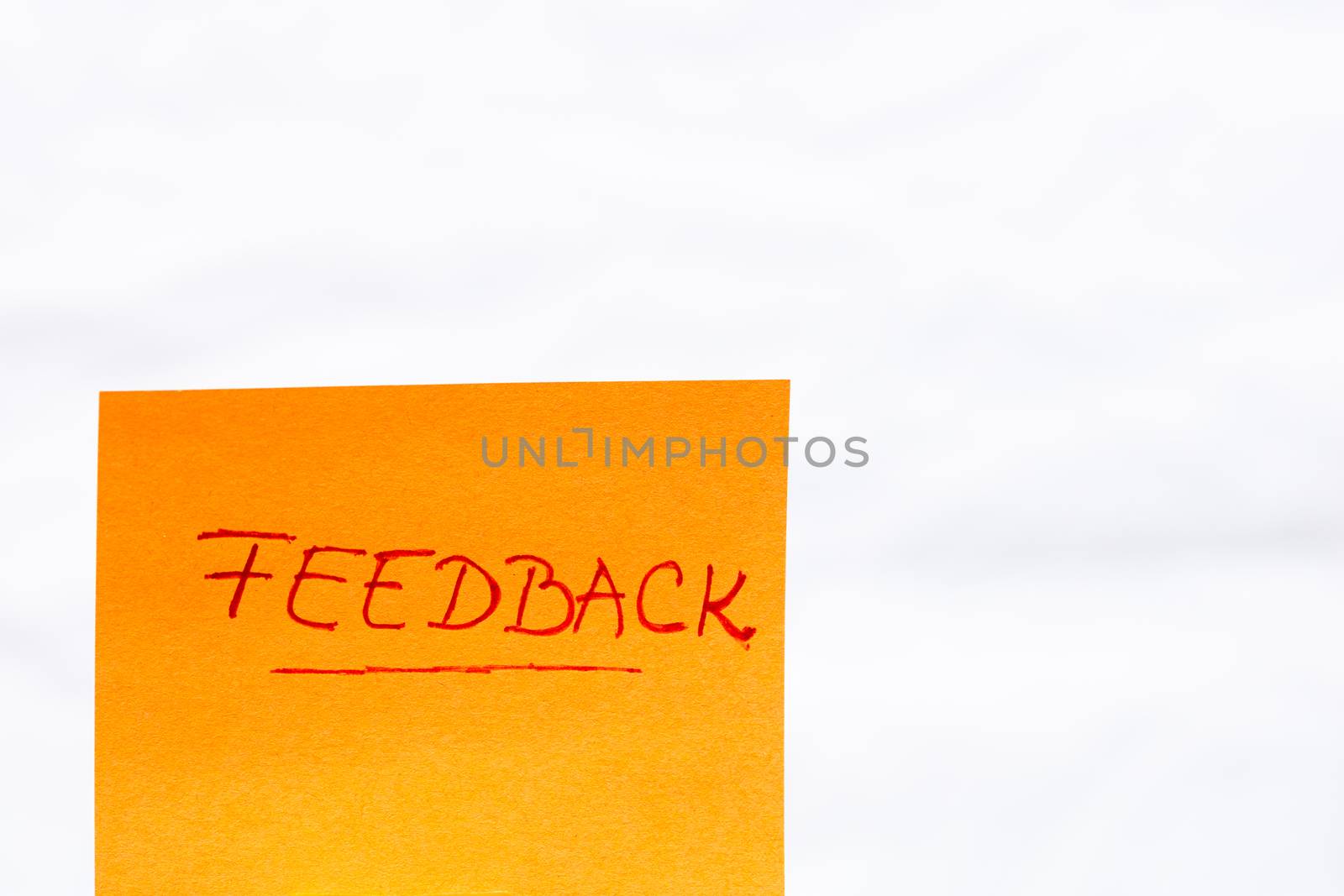 Feedback handwriting text close up isolated on orange paper with copy space.