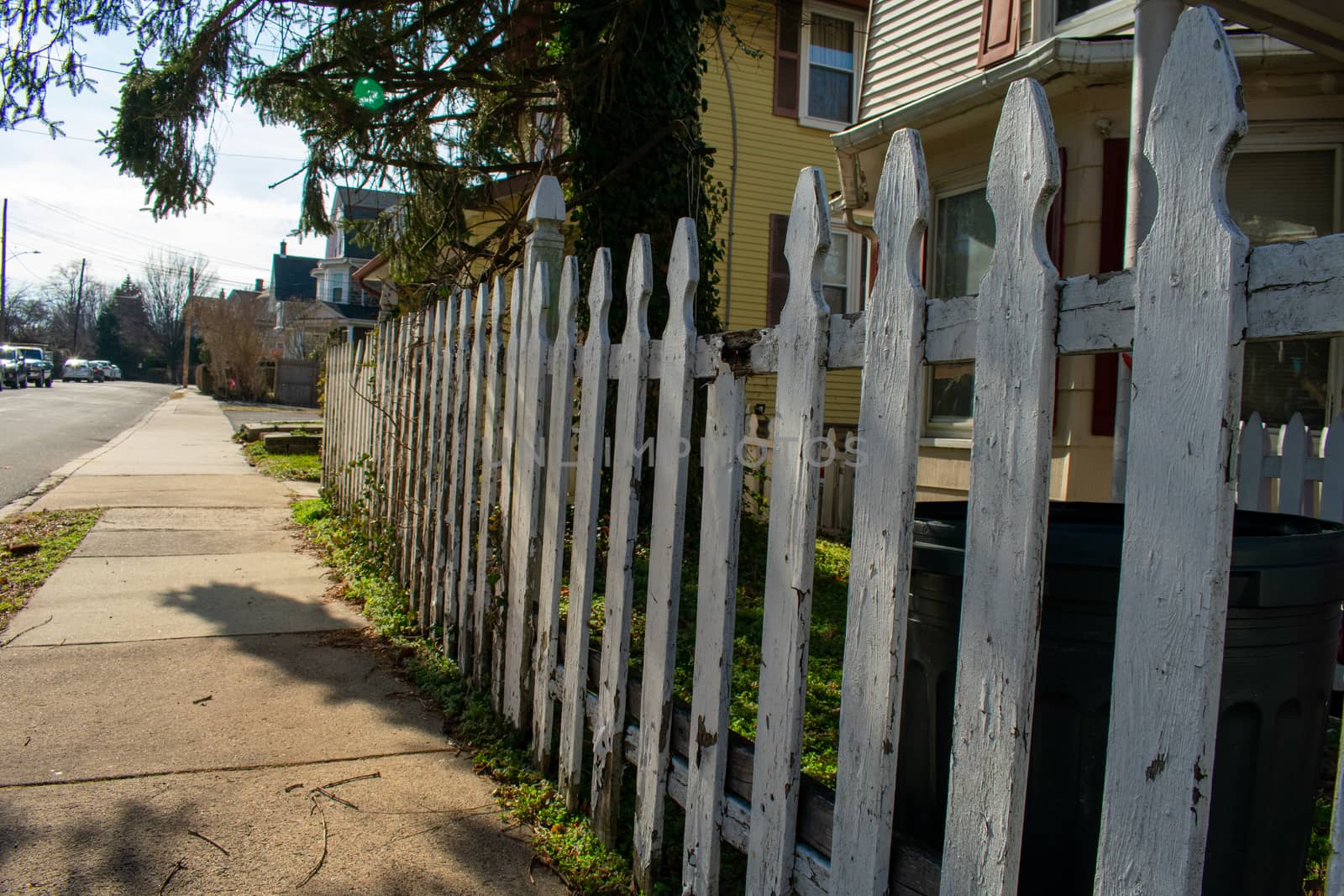 An Old and Broken White Wooden Fence on a Suburban Street by bju12290