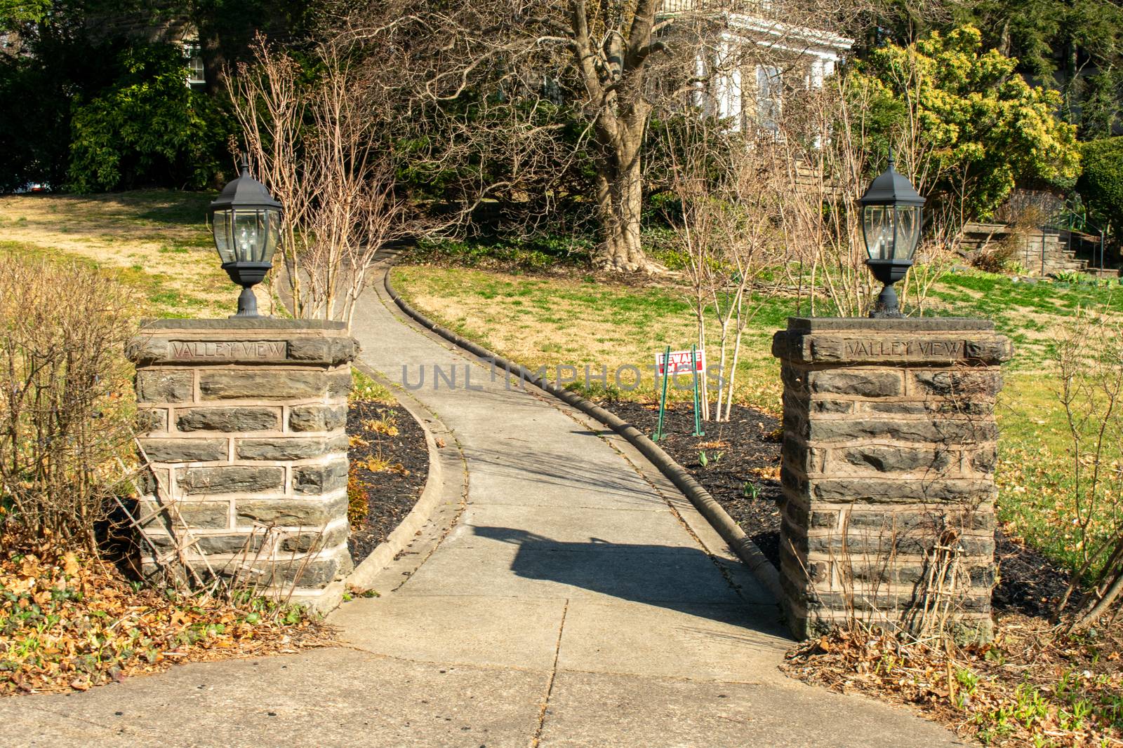 Two Cobblestone Pillars With Lights on Top and a Paved Path Running Between Them