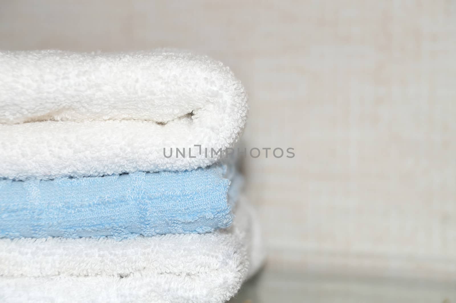 folded terry towels on a light background close up by Annado