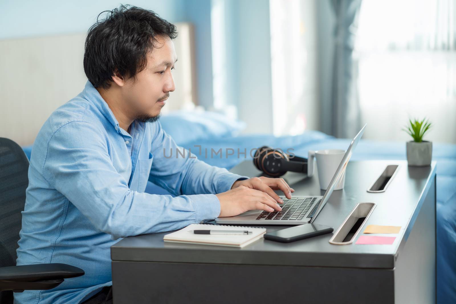 Asian business man using technology laptop and working from home by Tzido