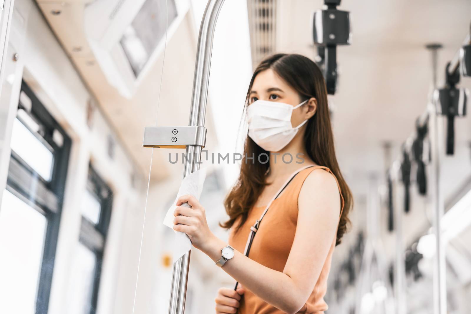 Closeup hand touching with wet wipe of Young Asian woman passenger wearing surgical mask in subway train when traveling in big city at Covid19 outbreak, Infection and Pandemic, new normal concept