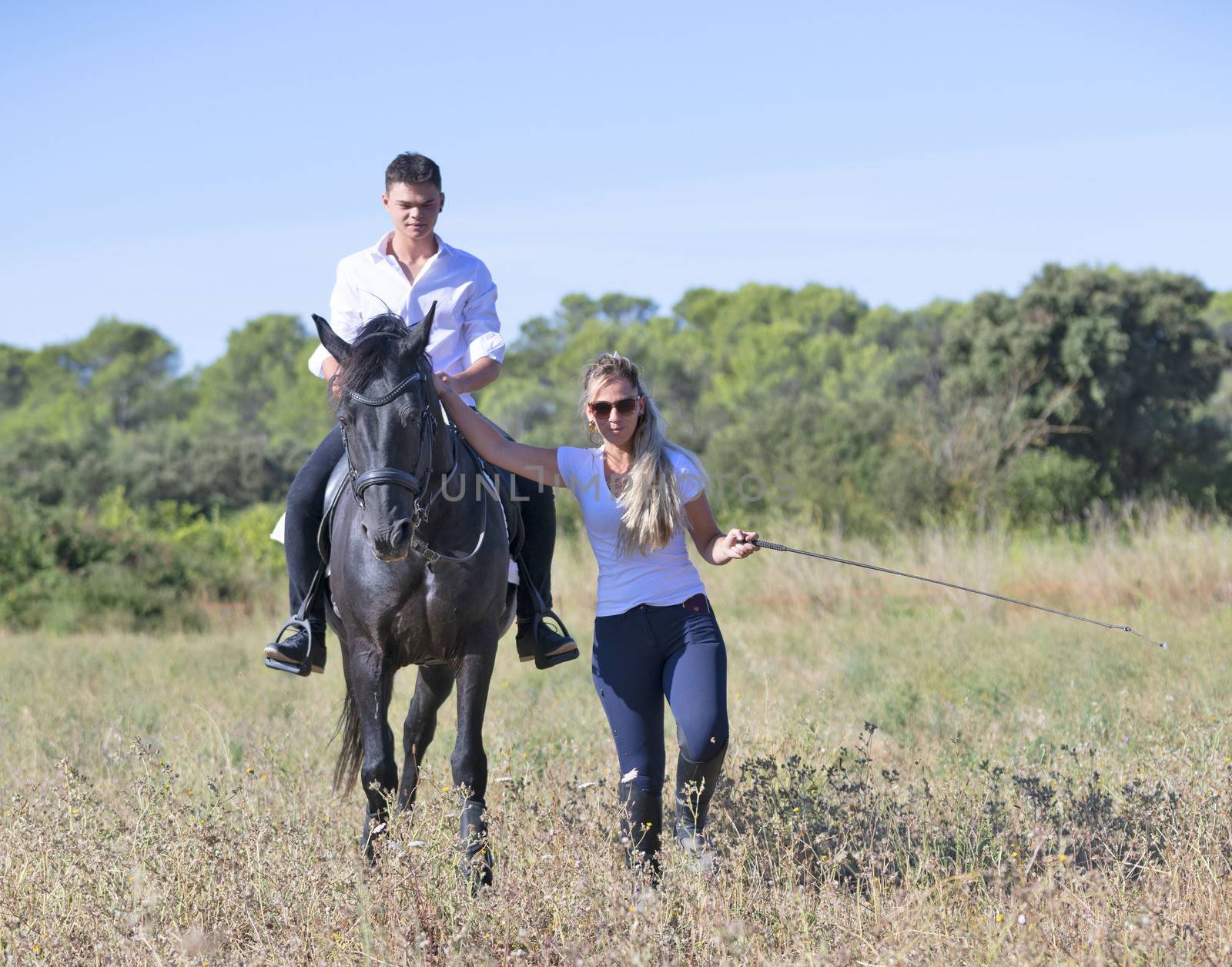  riding teenager are training her black horse with teacher