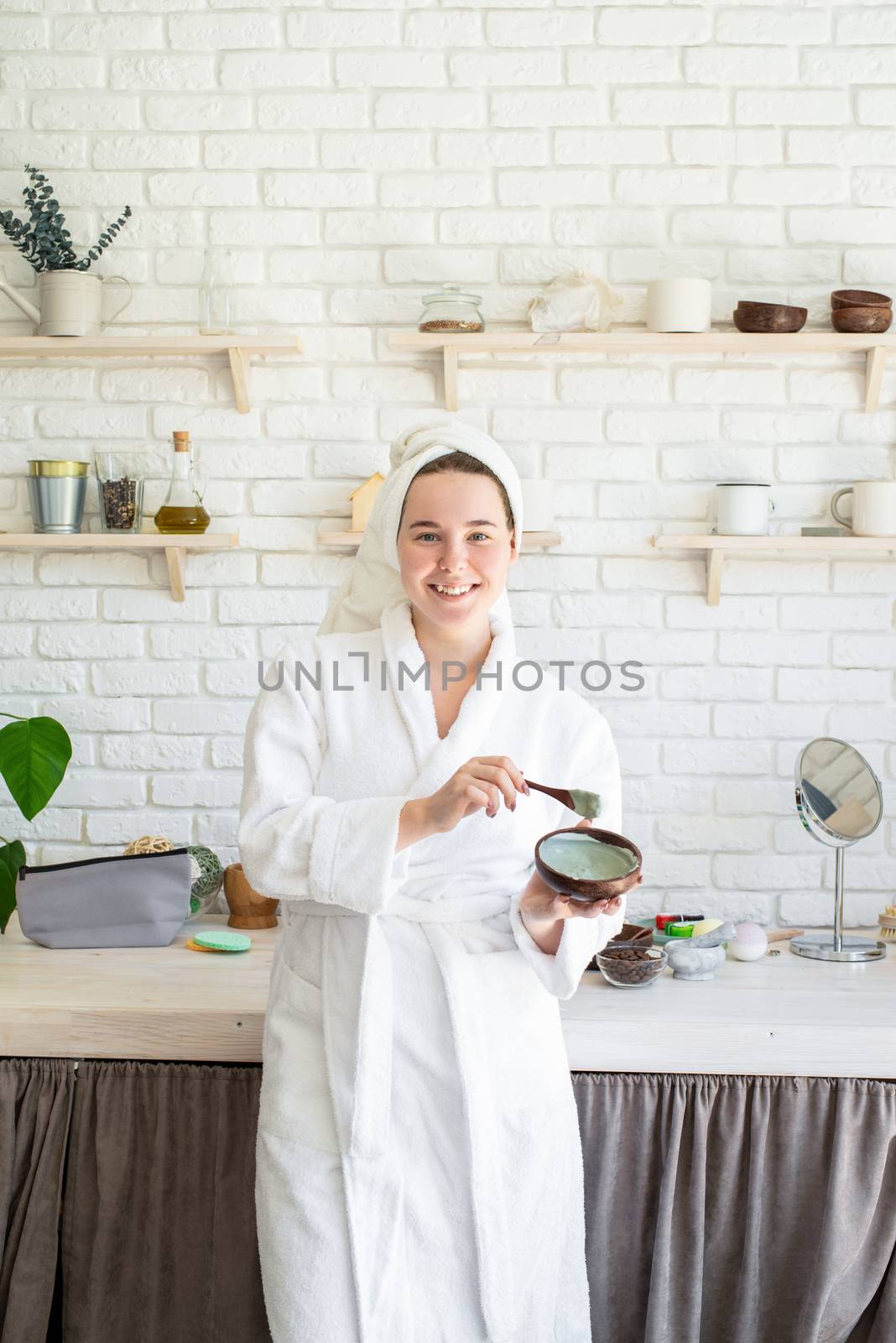 Spa and wellness. Natural cosmetics. Self care. Happy young woman applying face scrub on her face in her home kitchen