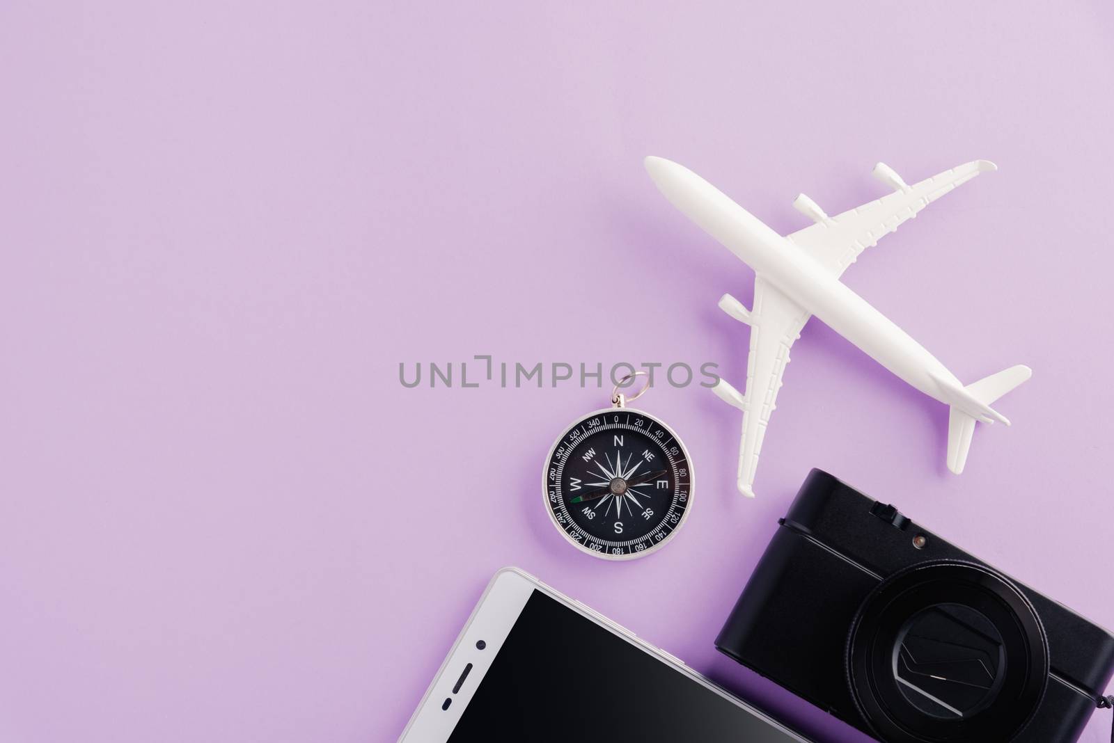 World Tourism Day, Top view of minimal model plane, airplane, starfish, alarm clock, compass, camera and smartphone, studio shot isolated on a purple background, accessory flight holiday concept