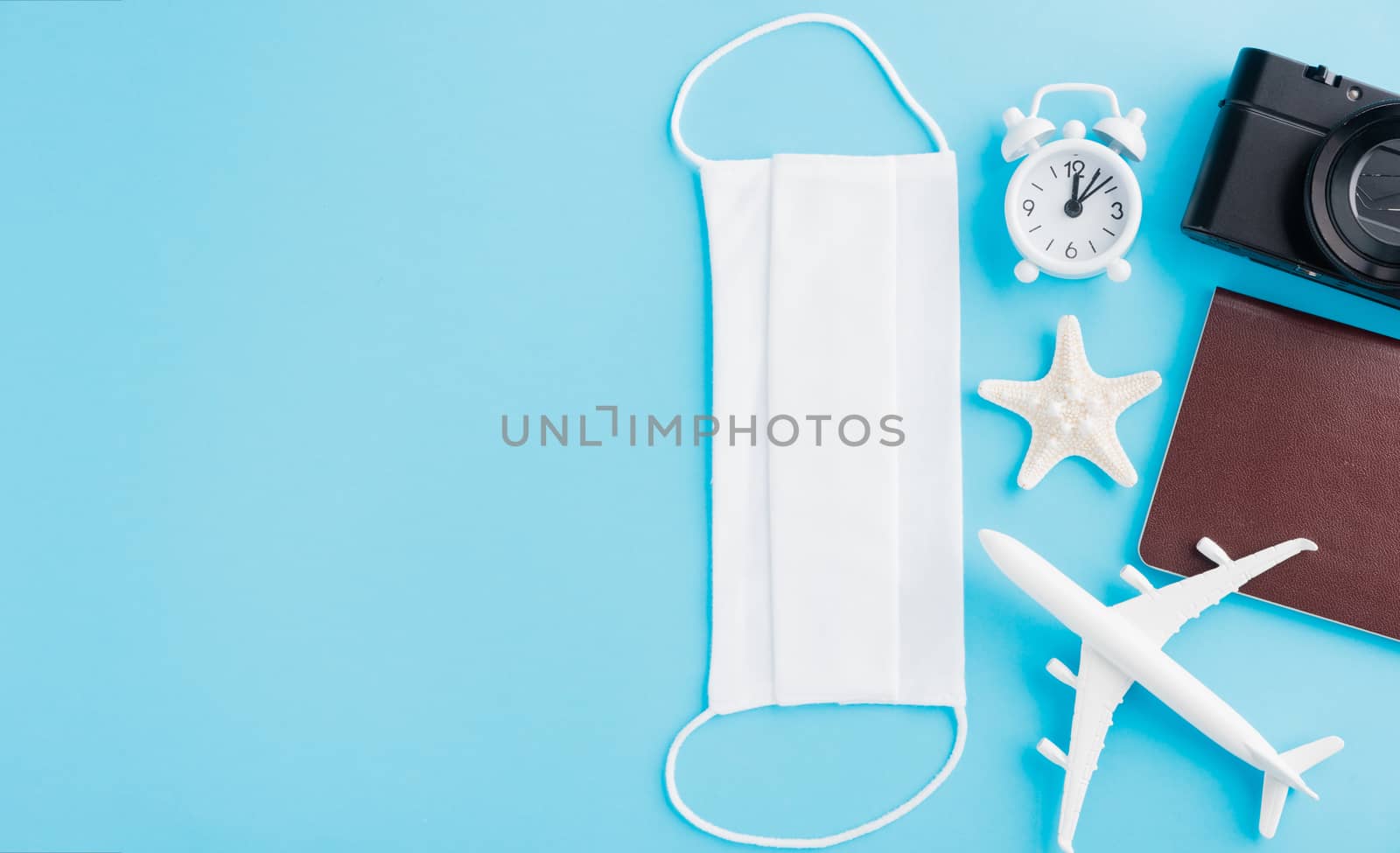 World Tourism Day, Top view of minimal model plane, airplane, starfish, compass, smartphone blank screen and face mask isolated on blue background, accessory flight holiday under coronavirus concept