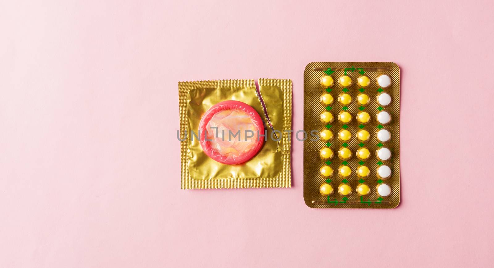 World sexual health or Aids day, condom on wrapper pack and contraceptive pills blister hormonal birth control pills, studio shot isolated on a pink background, Safe sex and reproductive health concept