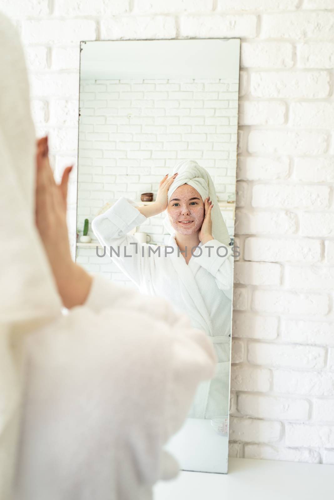 Spa and wellness. Natural cosmetics. Self care. Happy young woman applying face scrub on her face