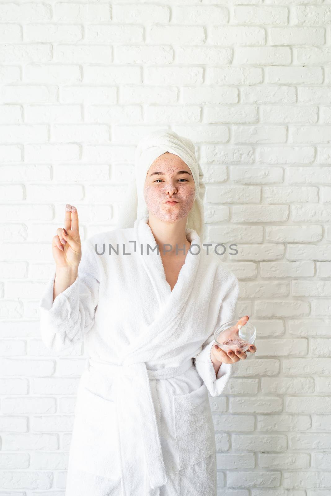 Happy young woman applying face scrub on her face by Desperada