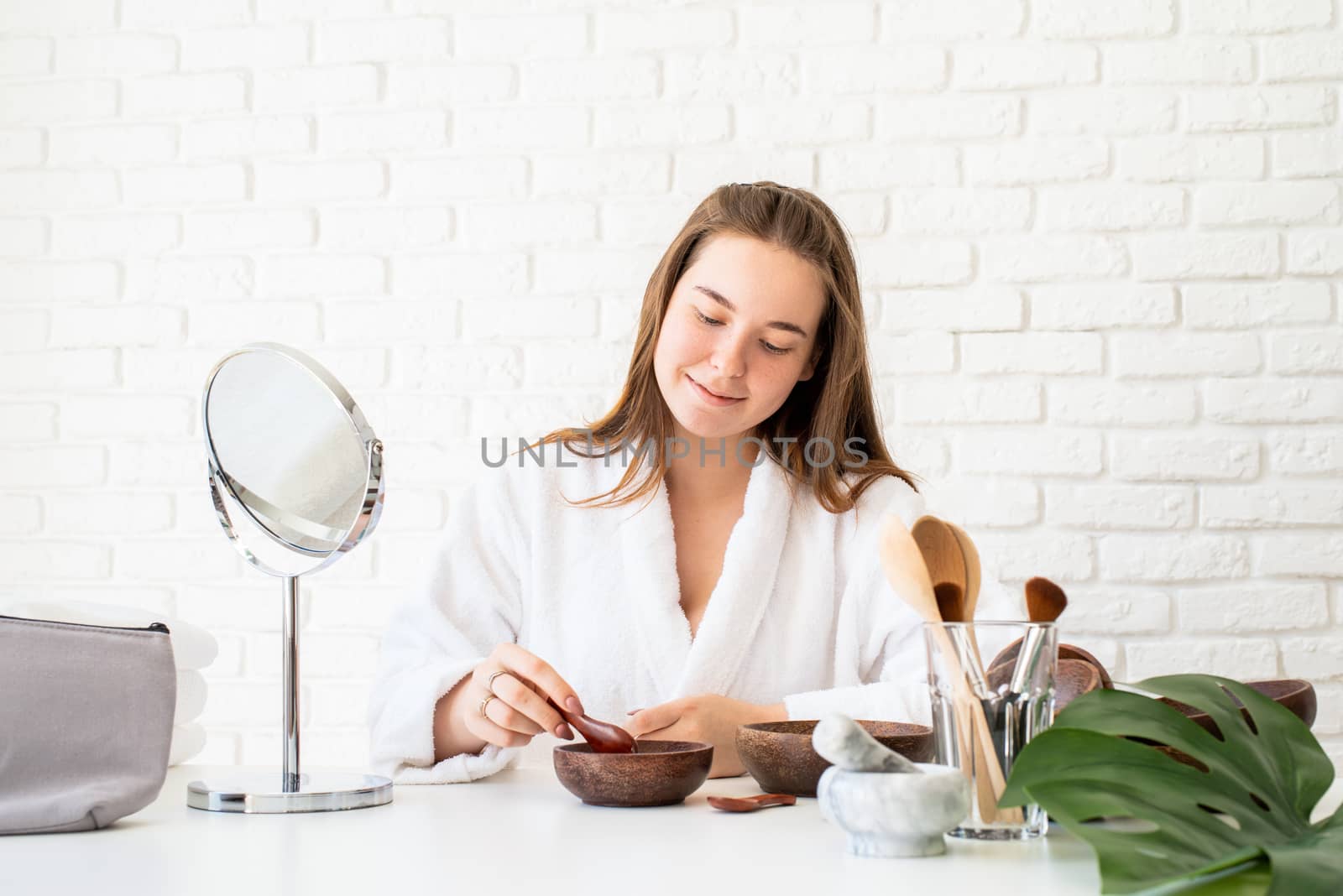 Spa and wellness. Natural cosmetics. Self care. Young caucasian woman wearing bathrobes doing spa procedures using natural cosmetics