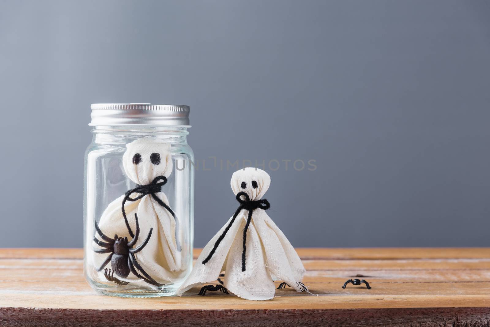 Funny Halloween day decoration party, closeup white ghost and spider in jar on wooden wall gray background and copy space, studio shot isolated, Happy holiday concept