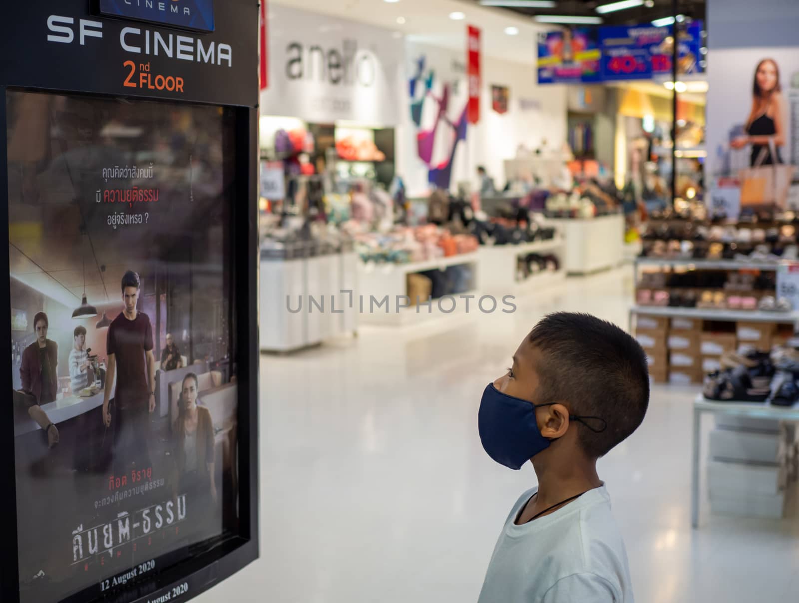 Prachinburi, Thailand 22/8/2020 Editorial illustrations Of a boy wearing a protective mask Standing and watching the billboard of the cinema In a mall in Thailand While the global coronavirus outbreak continues.