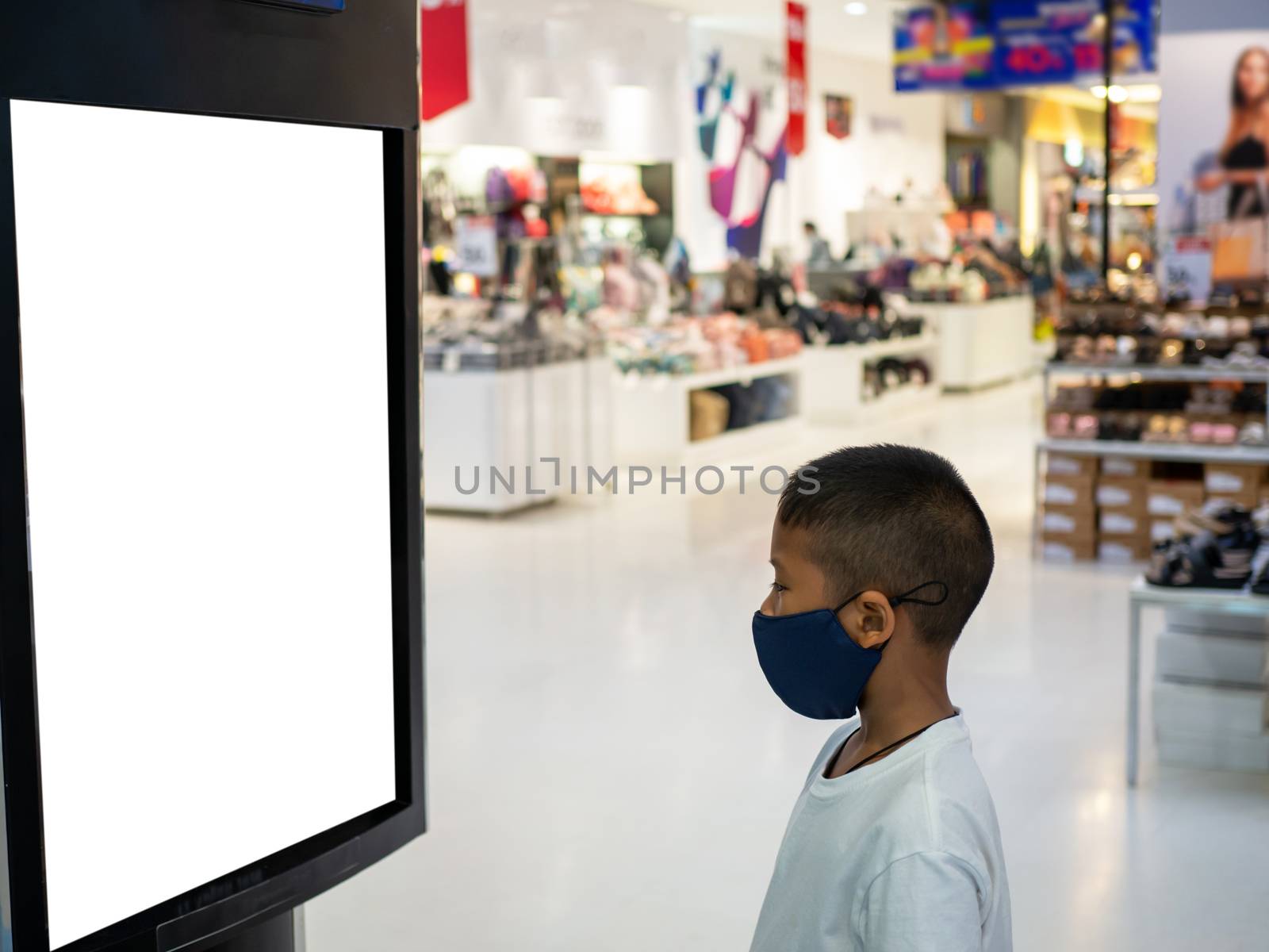 A boy wearing a mask Looking at an empty billboard in the mall by Unimages2527