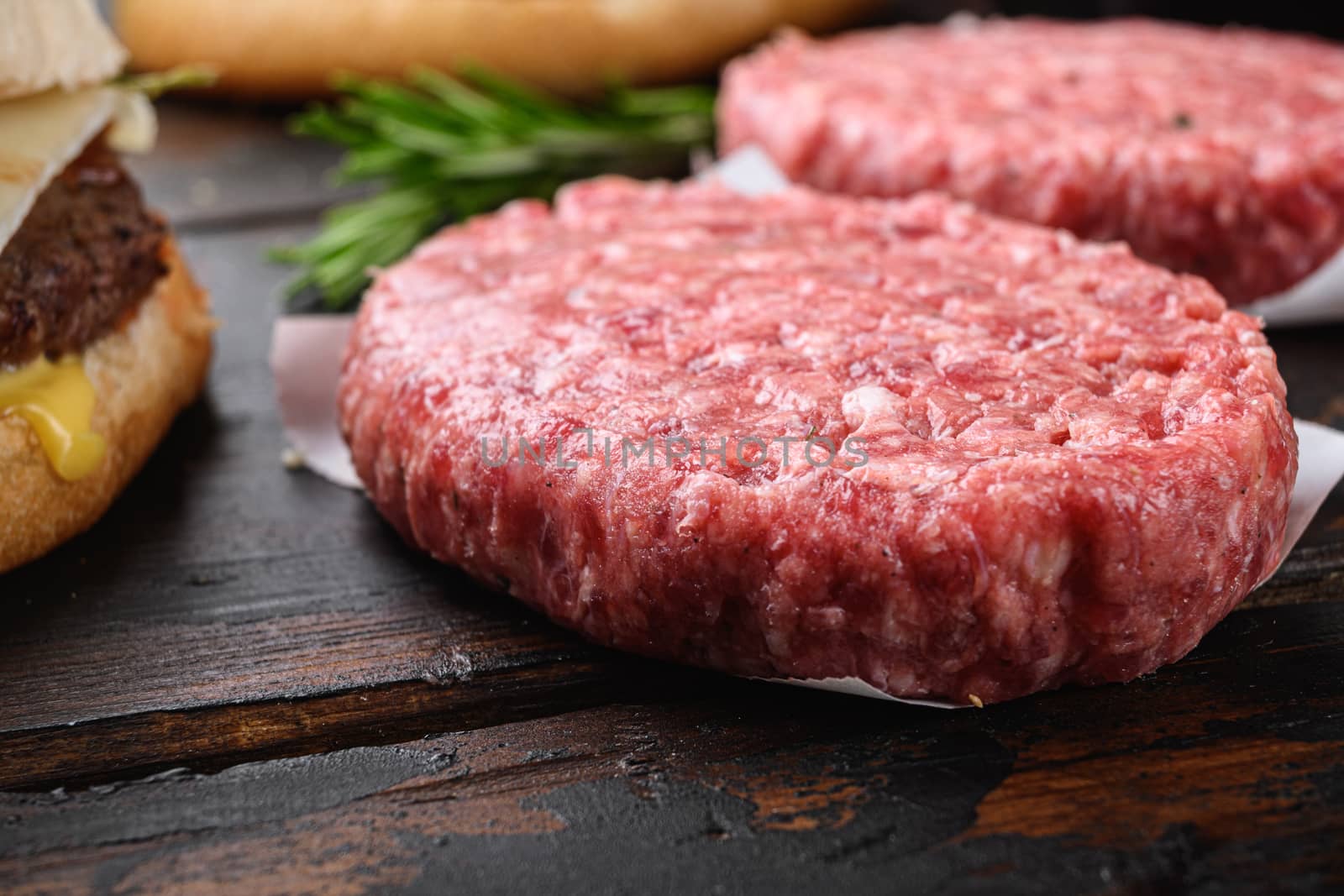 Ground beef organic cutlets on dark wooden background.