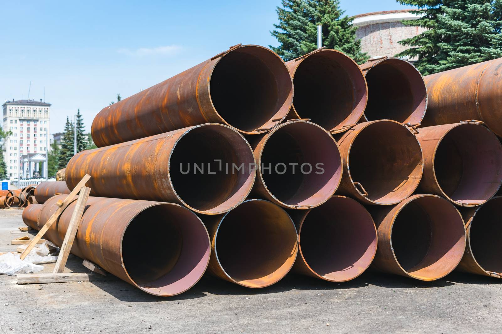 Large, old and rusty sewer pipes stacked in one batch for recycling