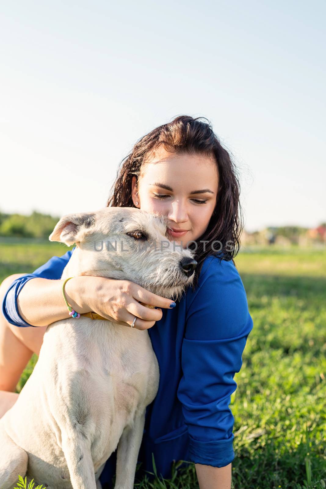 Pet care. Pet adoption. Beautiful young woman in sitting in grass with her mixed-breed dog pet
