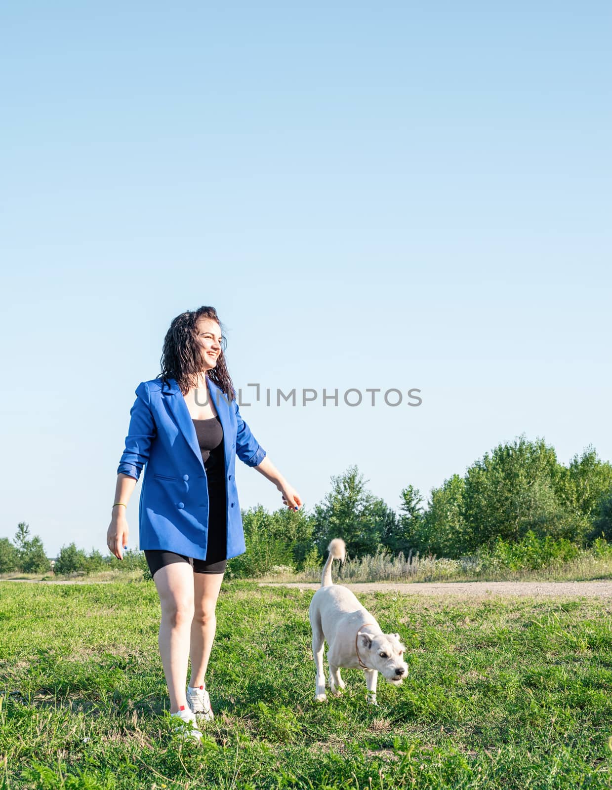 Pet care. Pet adoption. Young woman walking her dog in the park in a summer sunny day