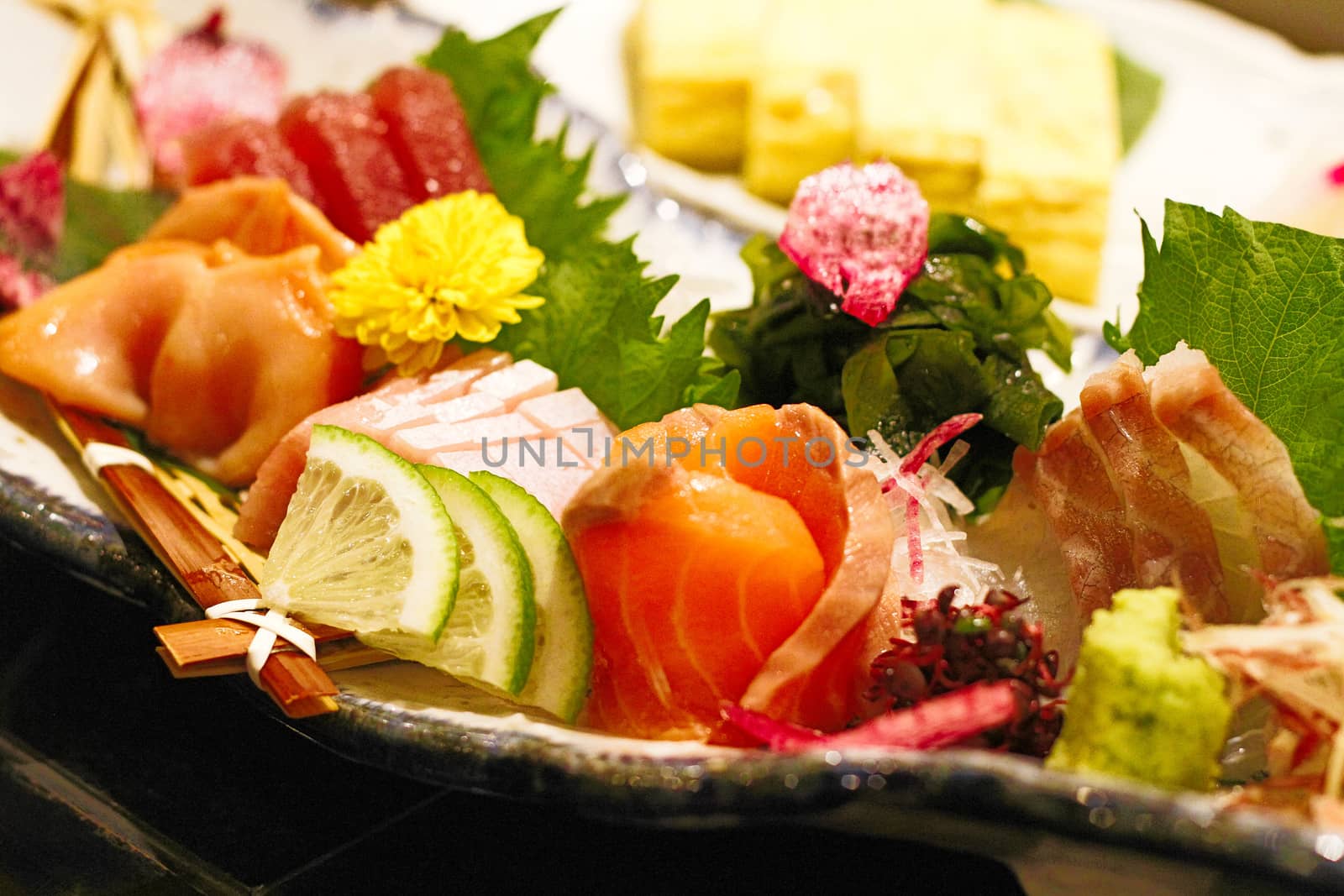 Correct authentic sashimi dish plate unique to Japan.Japanese food style with raw fishes with green leaves - cinematic color in film style with flare light