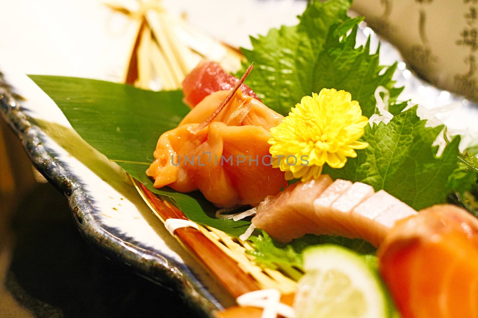 Correct authentic sashimi dish plate unique to Japan.Japanese food style with raw fishes with green leaves - cinematic color in film style with flare light