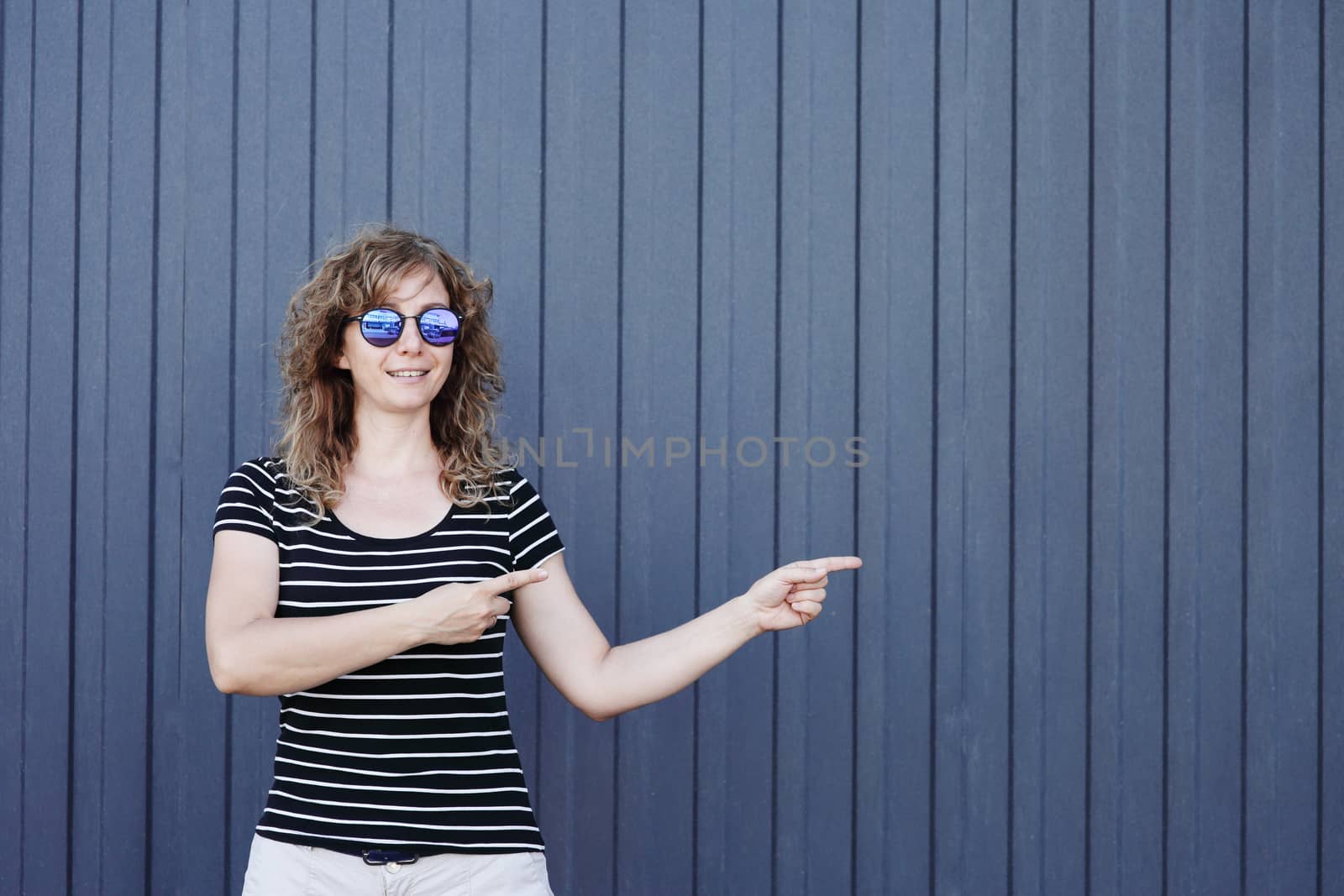 Woman portrait in sunglasses, free space for text. Blue striped wall in the background