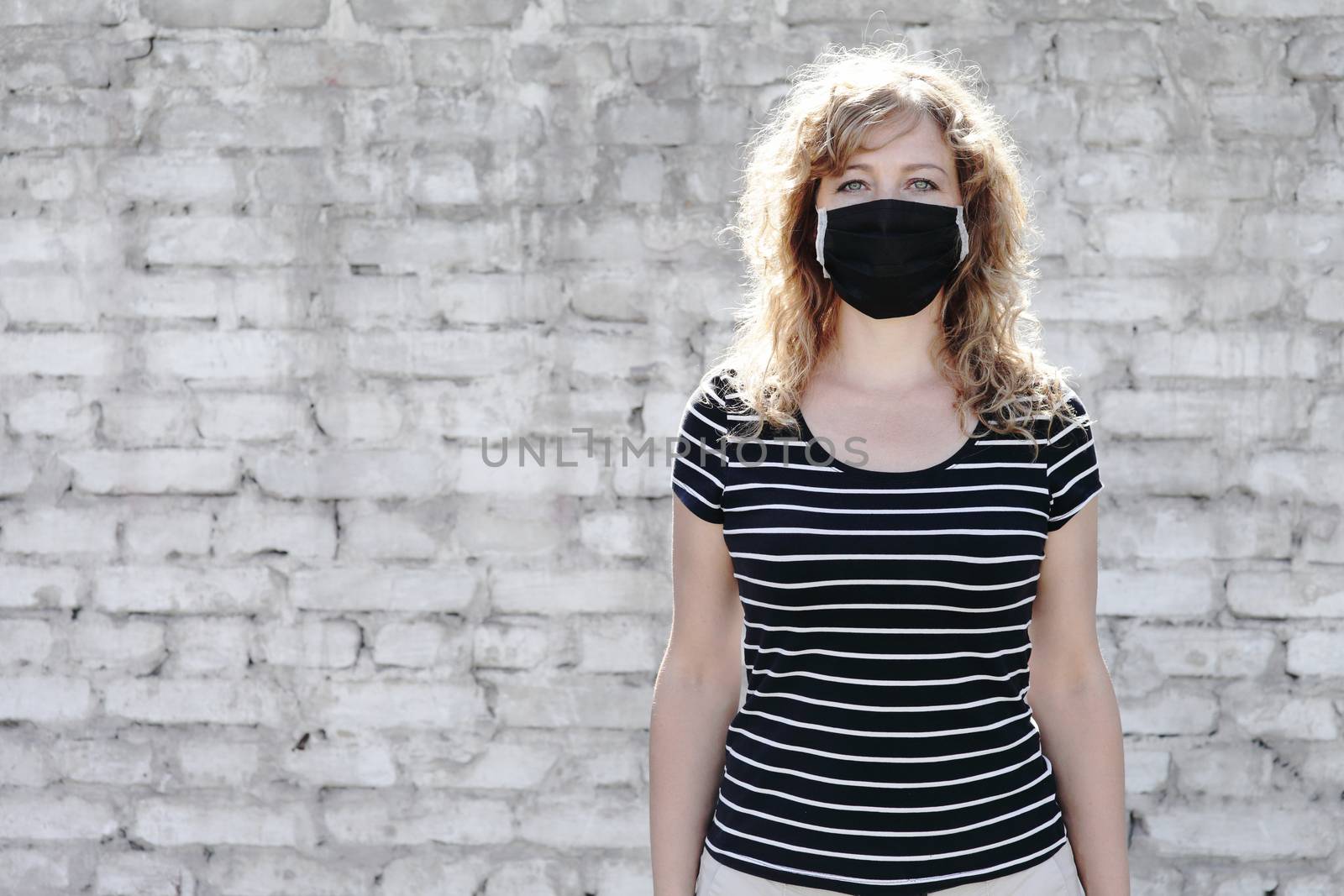 Portrait of a Girl in a protective mask, free space for text. Social distancing. White brick wall in the background. 