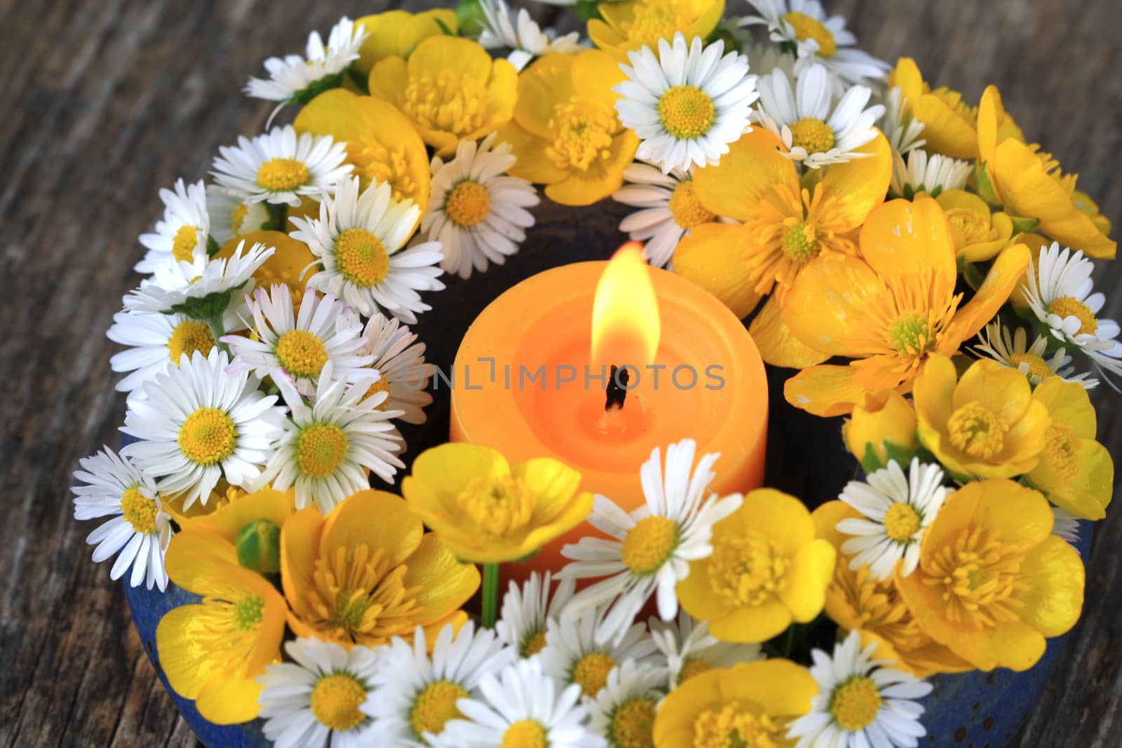 Summer flower decoration with daisies, buttercups and a candle