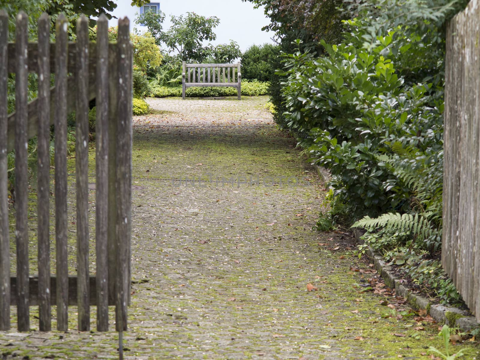 Open gate and entranceway leading to a wooden bench by Kasparart