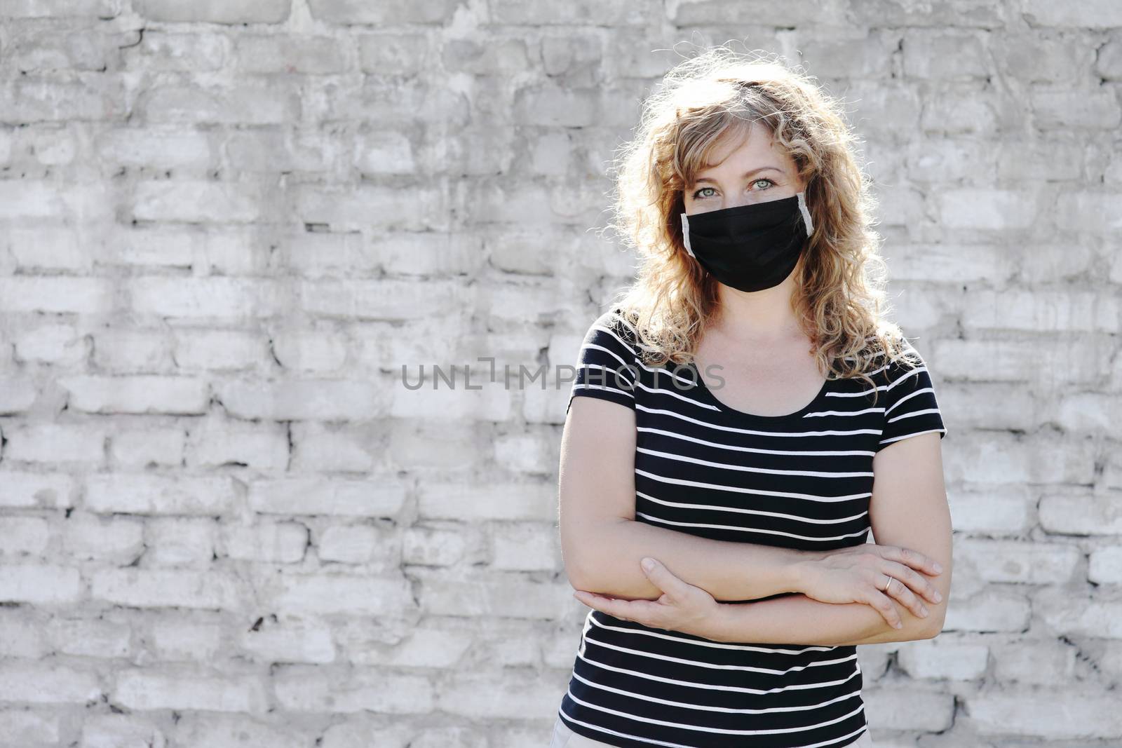 Portrait of a Girl in a protective mask, free space for text. Social distancing. White brick wall in the background. 