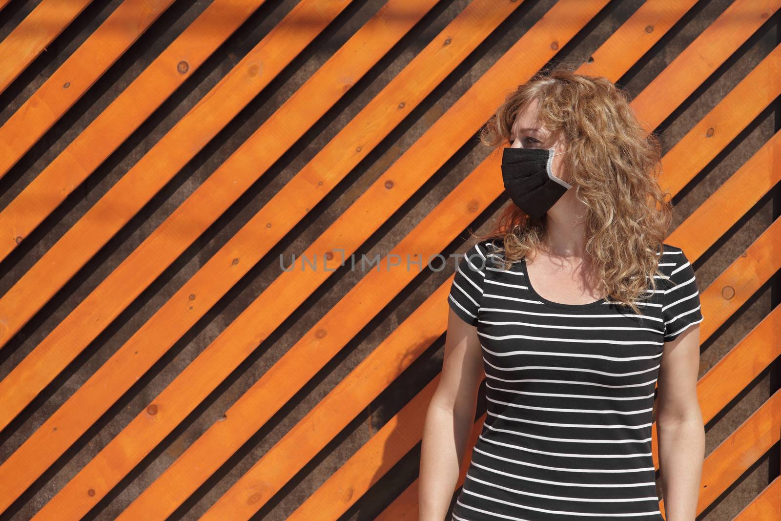 Portrait of a Girl in a protective mask, free space for text. Social distancing. Orange wooden wall in the background
