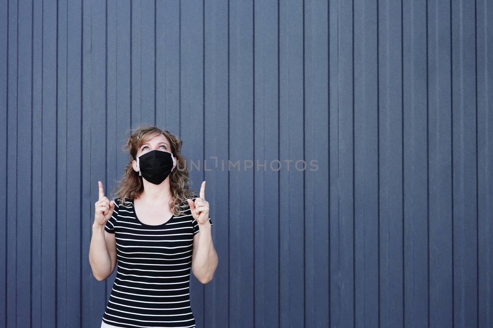 Portrait of a Girl in a protective mask, free space for text. Social distancing. Blue striped wall in the background