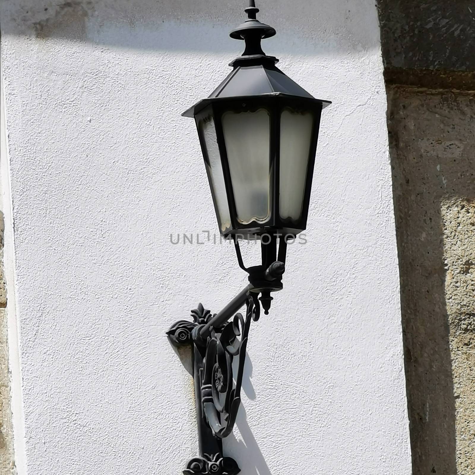 A lamp hanging from the side of a building. High quality photo