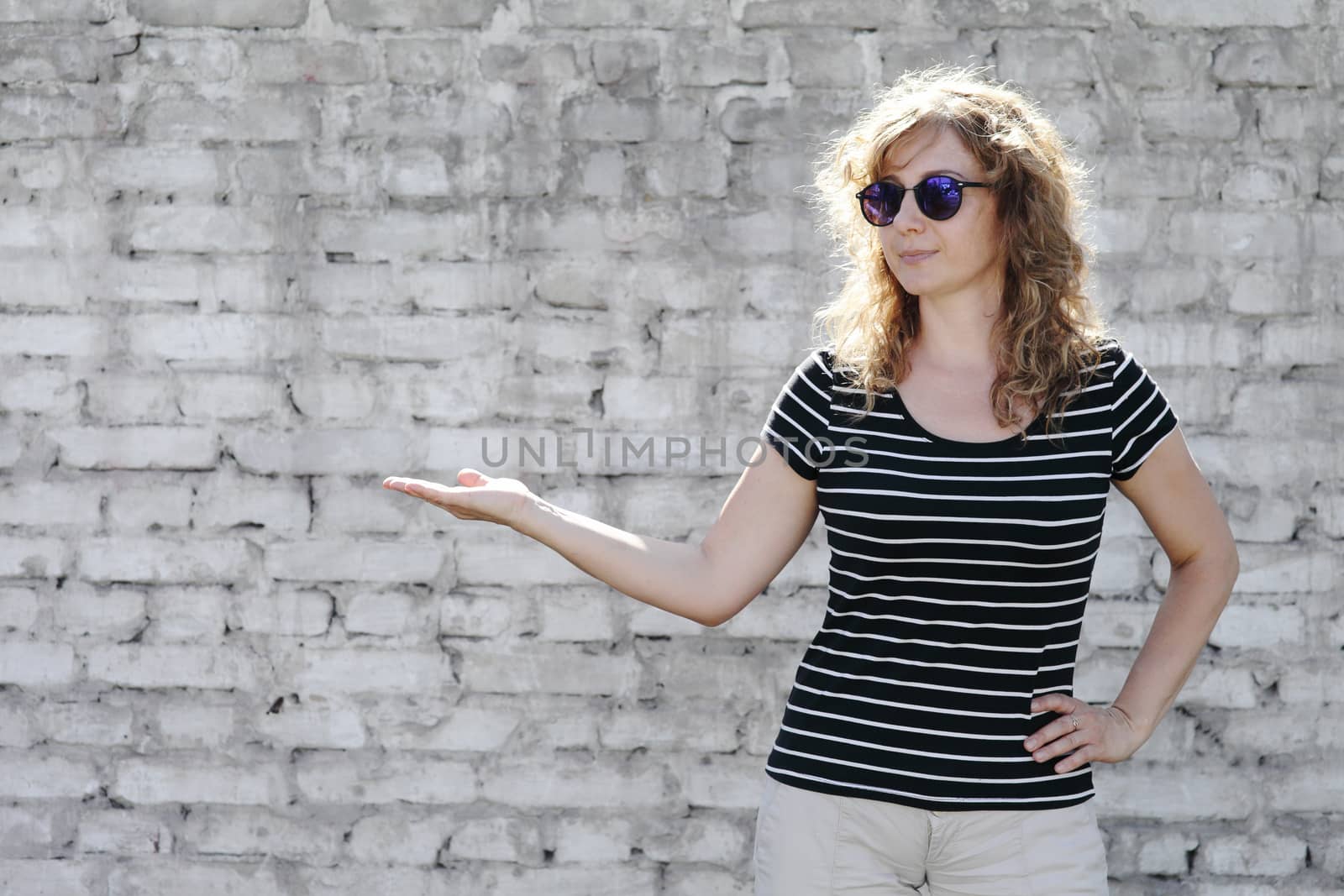 Woman portrait in sunglasses, free space for text. White brick wall in the background