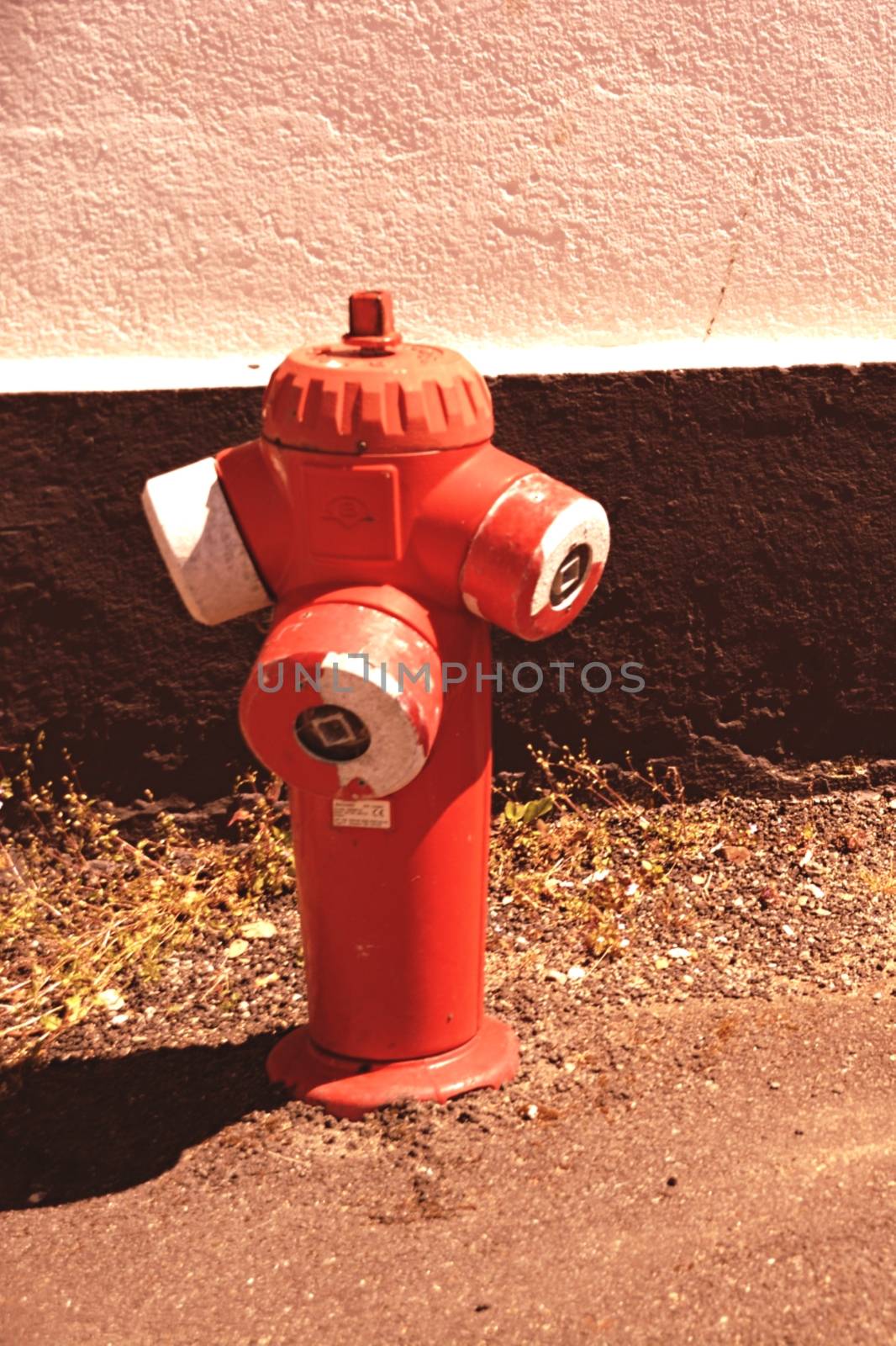 A fire hydrant sitting on the side of a building by balage941