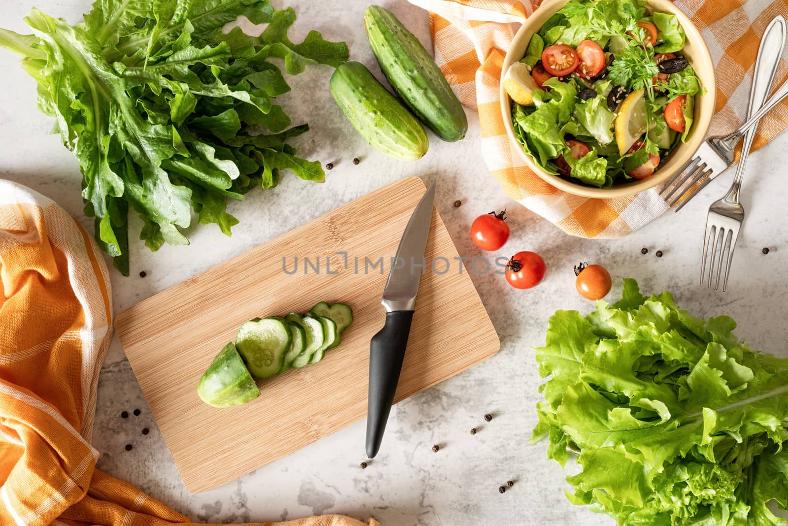 Healthy food concept. Top view of making vegetable salad with cutting board, bowl of salad and fresh organic vegetables