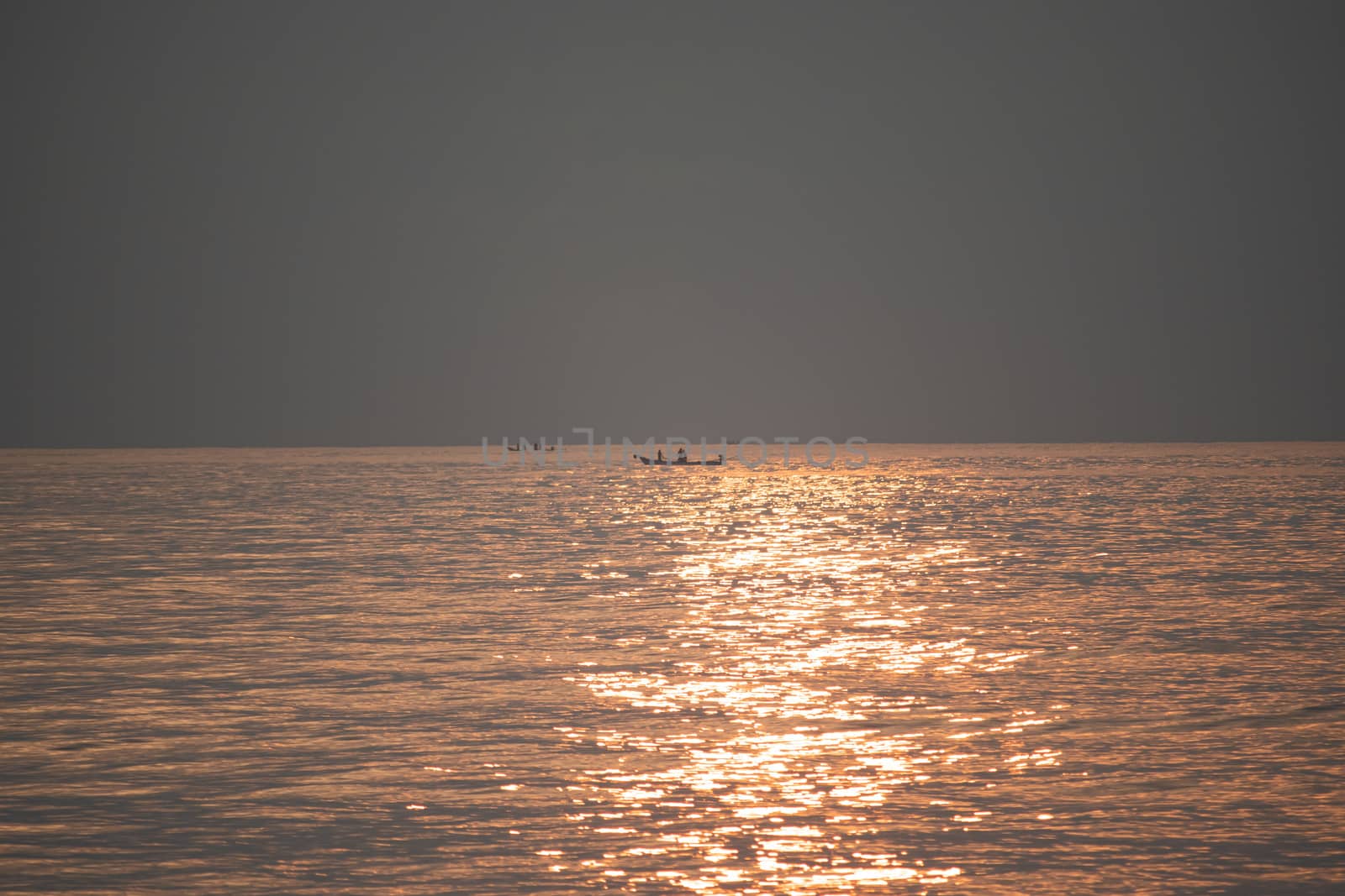 The sun's rays appear transparent in the sea water.Sunrise in the morning from the clouds at Kovalam beach in Chennai