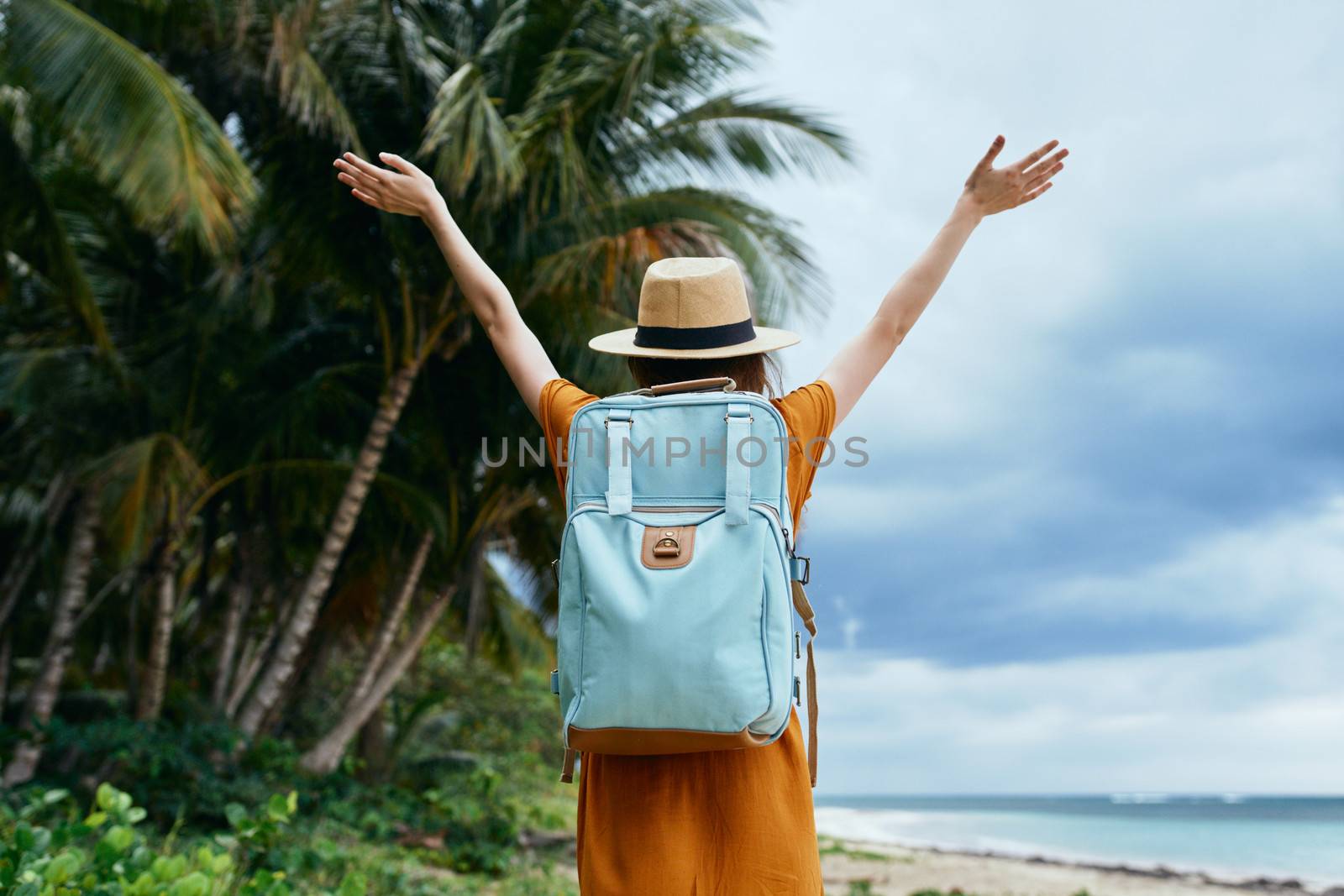 Woman tourist with blue backpack on her back with raised hands Freedom fresh air island travel