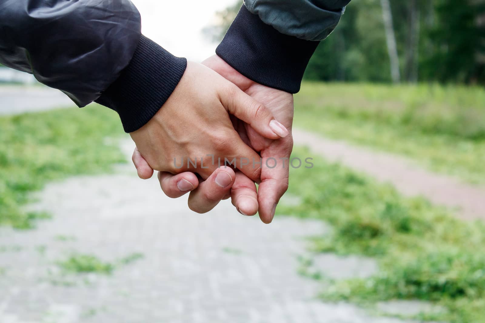 woman with a man holding a hand outdoor on summer day. hands closeup