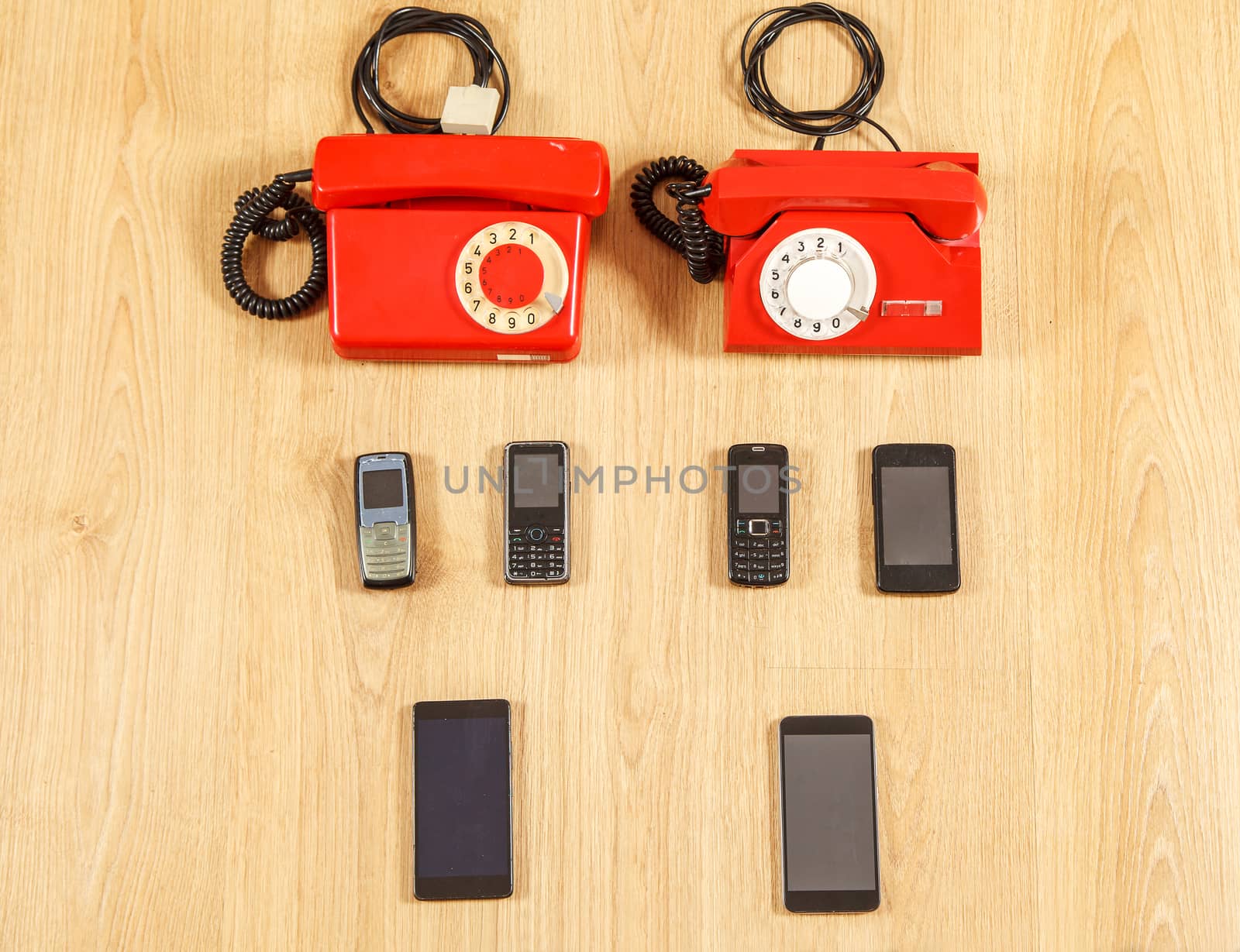 set of various old phones and modern smartphones on yellow wooden background. conceptual photo