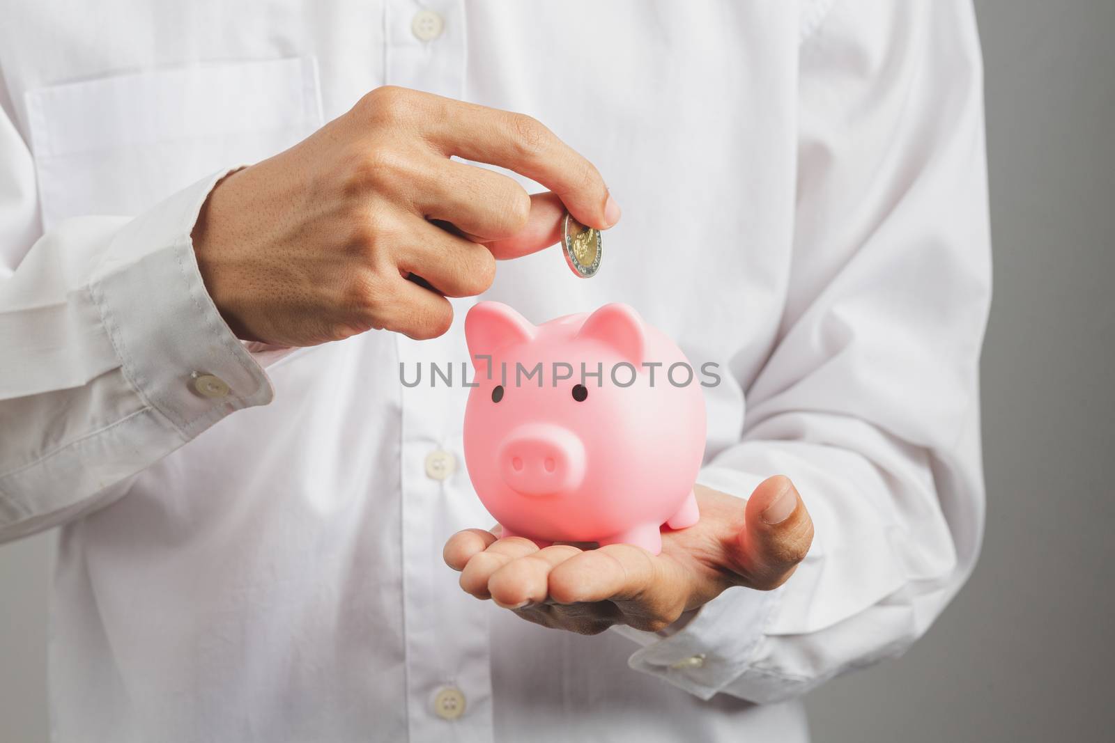 Hand of kid holding coin put in piggy bank with money stack grow by golfmhee